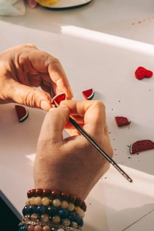 Hands crafting miniature watermelon pieces from polymer clay