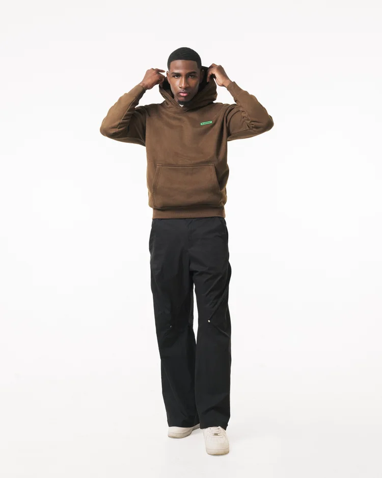 Full-length view of a model adjusting the hood of a brown R3 CONCEPT hoodie