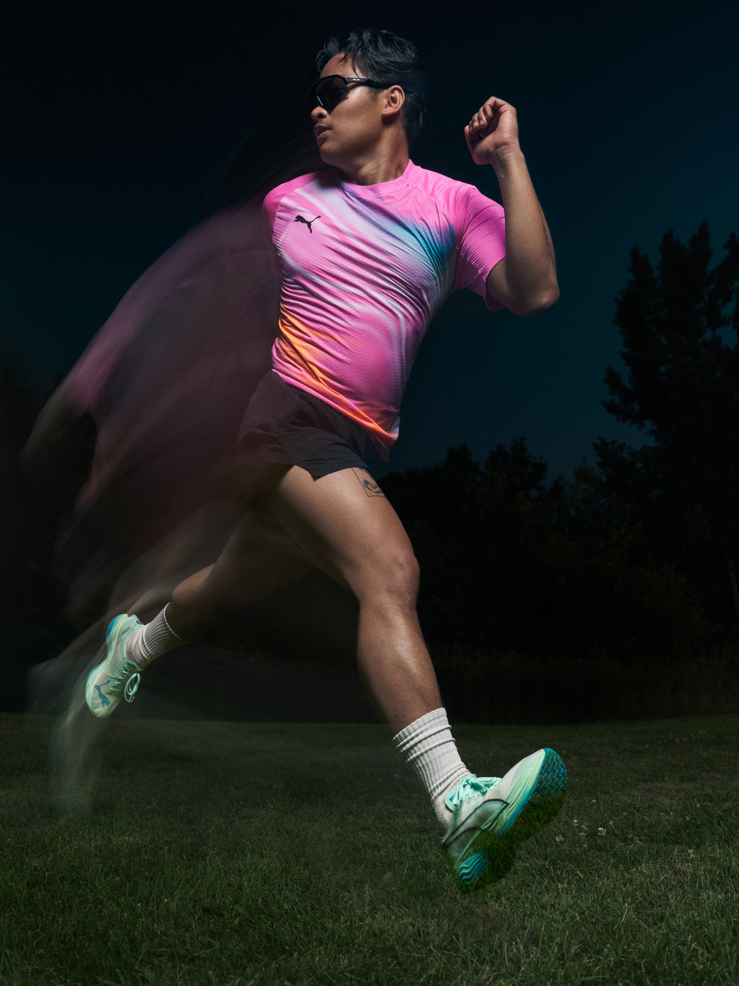 Commercial sportswear photograph of a runner in a pink Puma shirt with a motion trail at night
