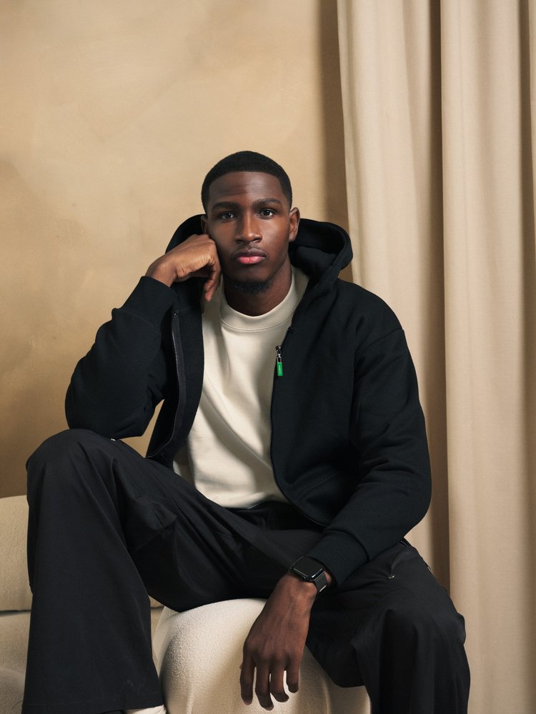 R3 CONCEPT black hoodie portrait against a warm studio backdrop