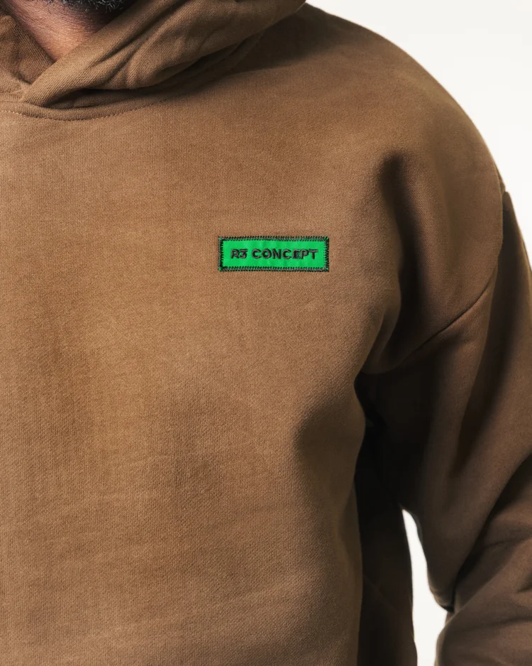 Green R3 CONCEPT logo patch and brown hoodie fabric photographed in close detail