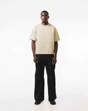 Full-length front view of a cream R3 CONCEPT T-shirt with black trousers