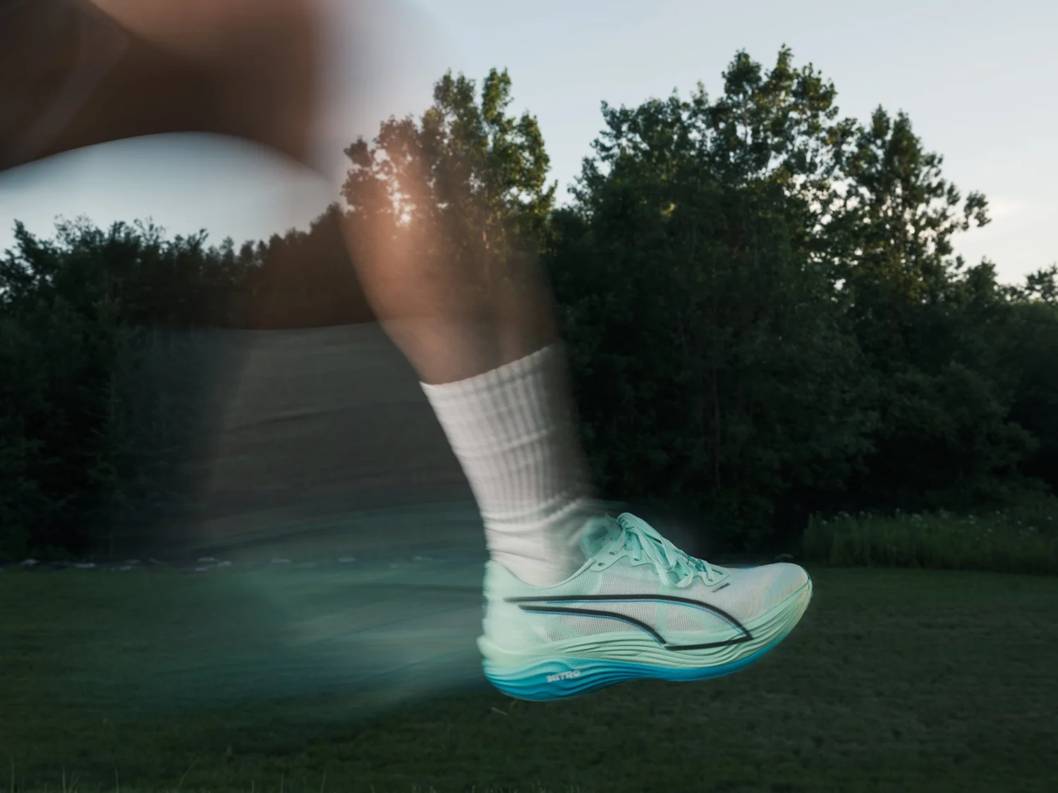 Close-up of a PUMA running shoe suspended above grass, with a motion trail