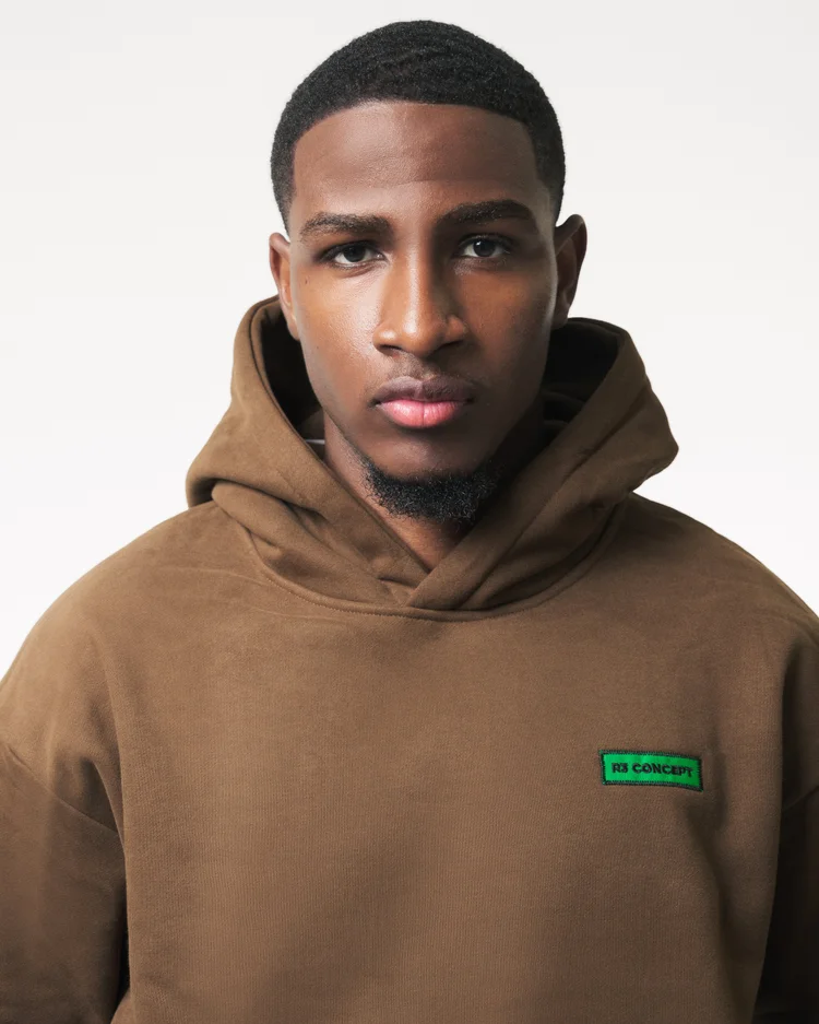 Front portrait showing the hood and green chest patch on a brown R3 CONCEPT hoodie
