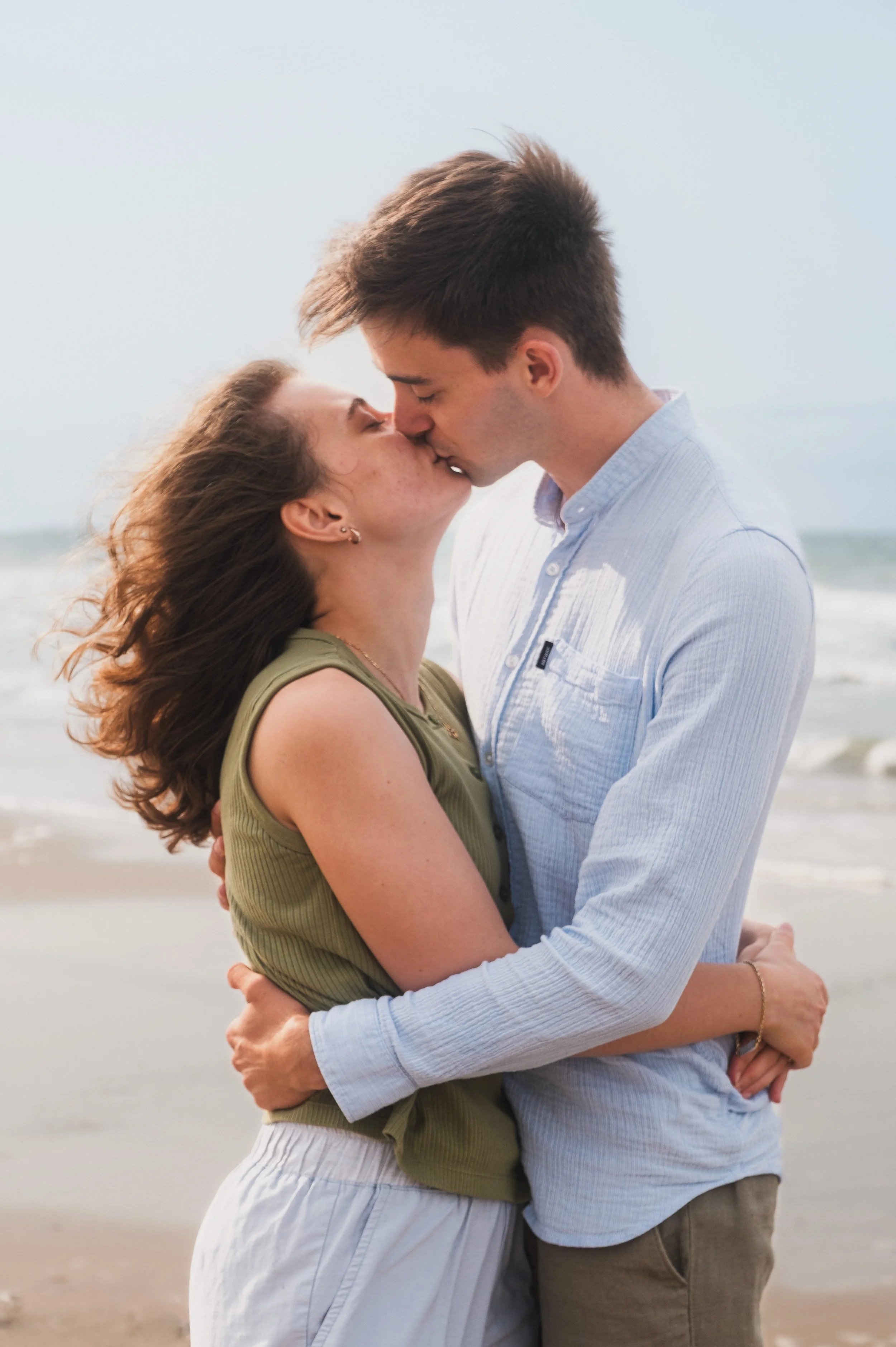 Couple qui s'embrasse au vent sur la plage, photographie de couple passionnée, Marion David photographe Bruxelles