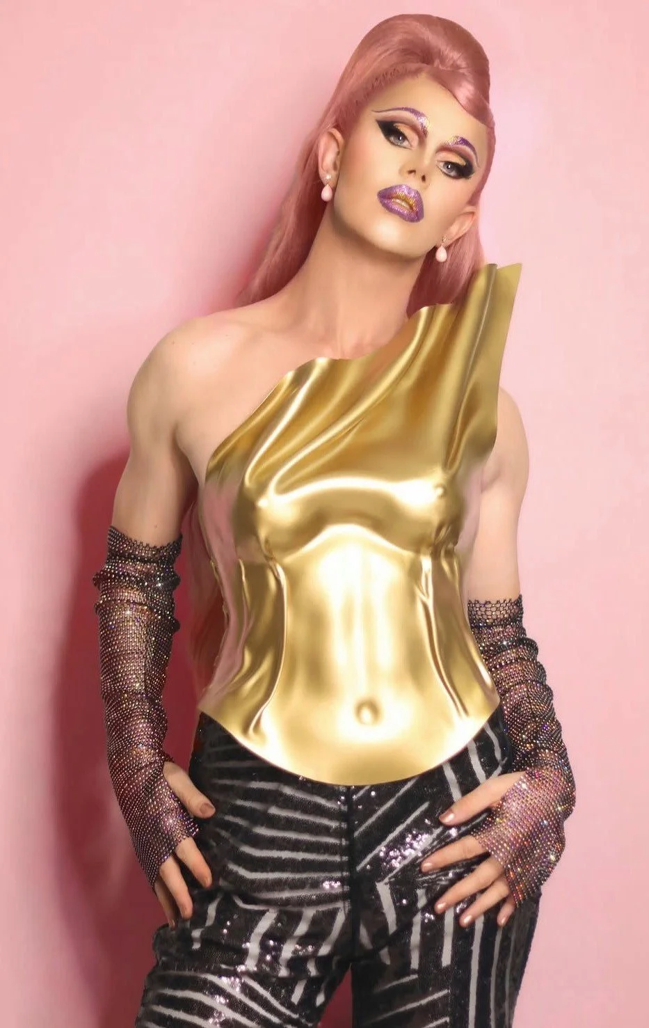 Midas with pink hair wearing a sculptural gold bodice and sparkling gloves
