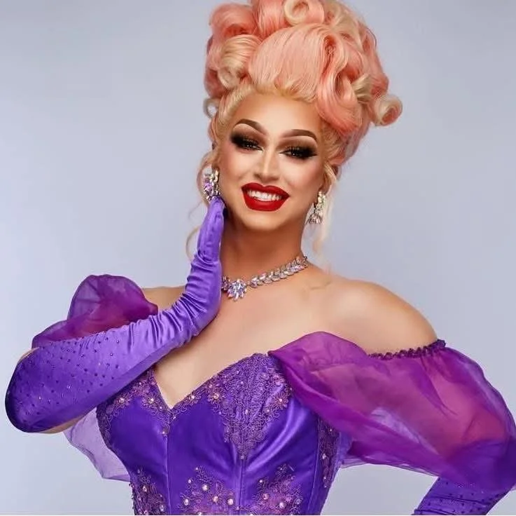 Sia Tequila with a pink-blonde updo, wearing a purple gown and long gloves