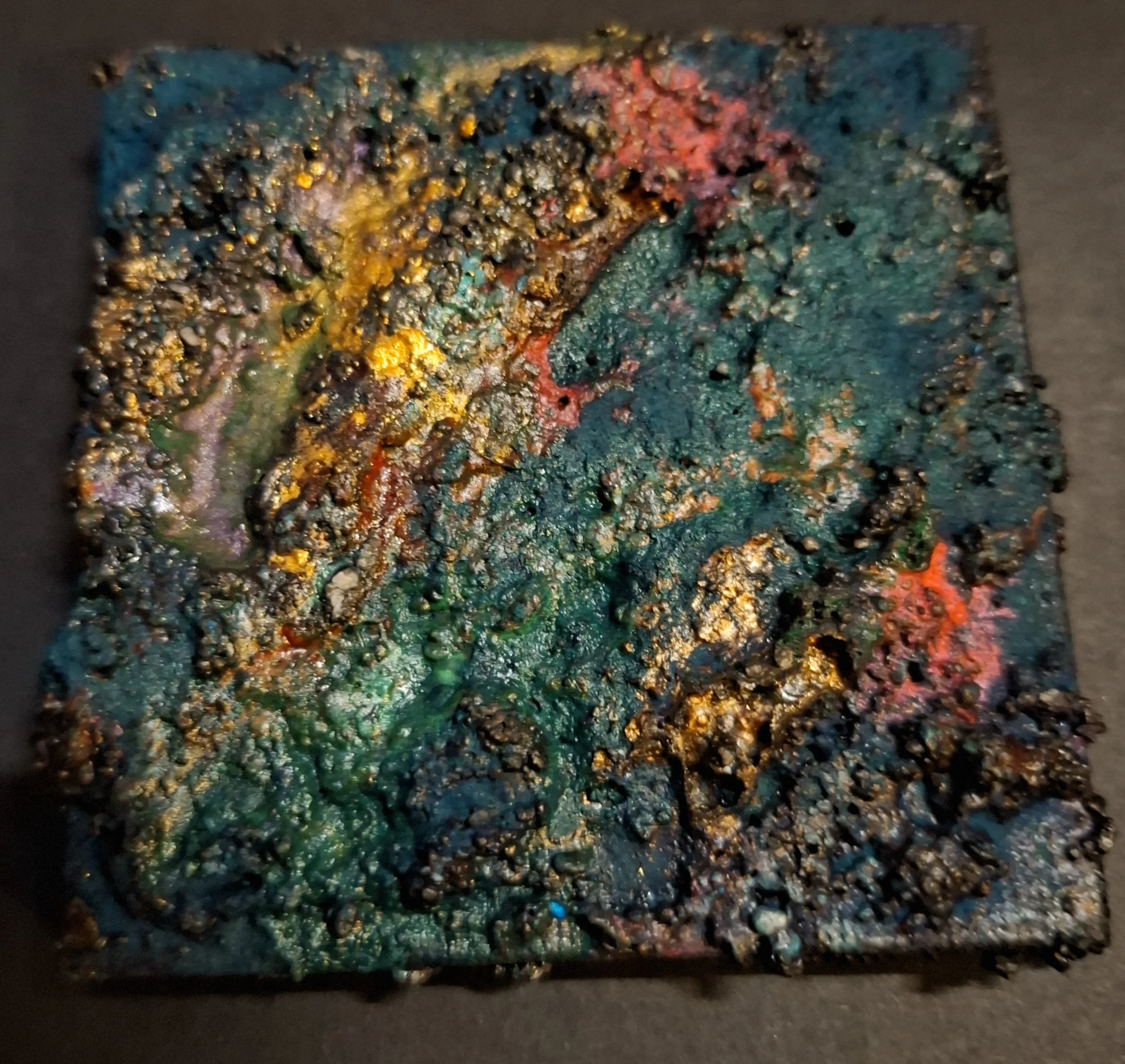 Mineralische Glutspur MF01 · magnetisches Sedimentfragment von Markus Willems Köln · 7×7 cm Mixed Media auf magnetischer Leinwand · türkis-grüne Mineraloberfläche mit goldenen Einschlüssen, dunklen Sedimentzonen und rötlicher Glutspur · Mikro-Original kaufen 55 Euro