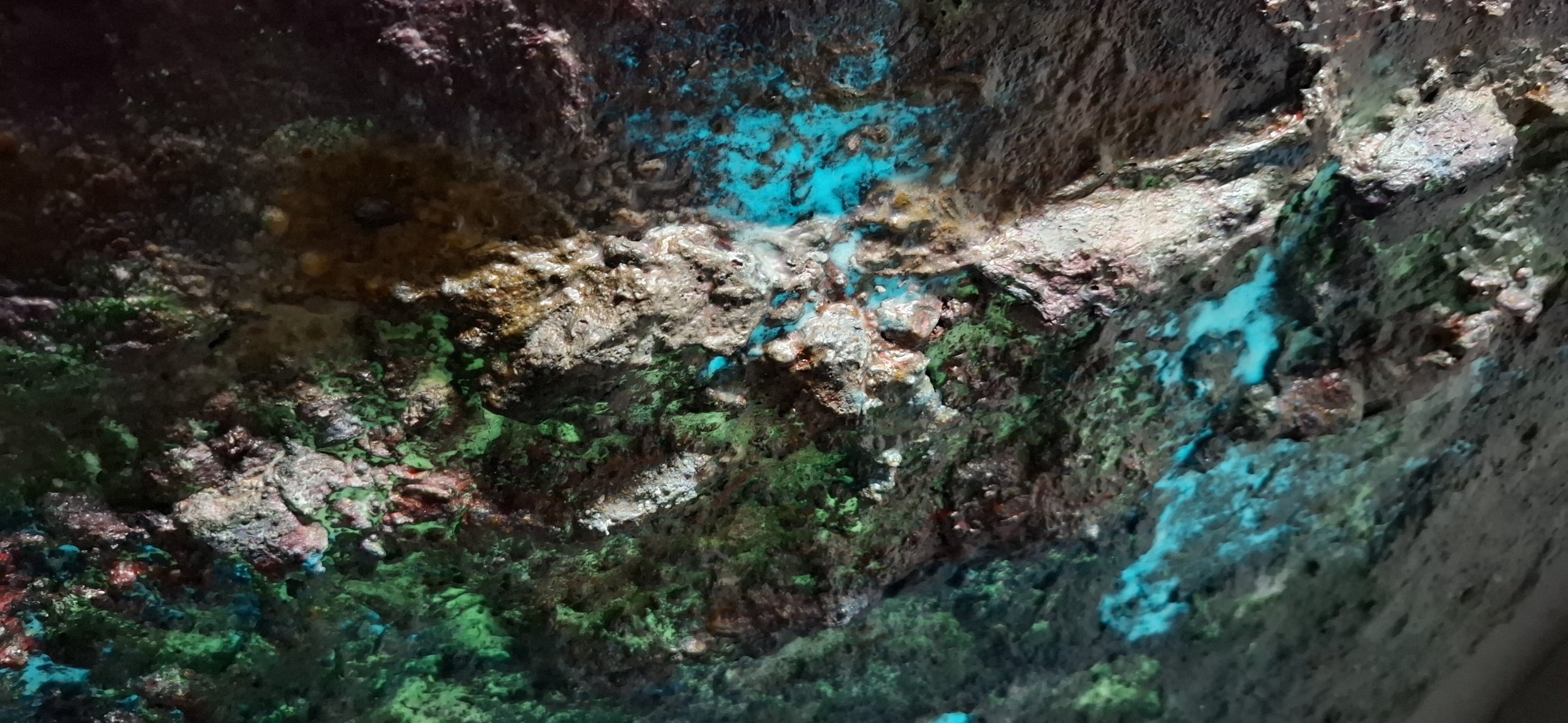 Nahaufnahme einer abstrakten Materialoberfläche mit türkisfarbenen, organischen und sedimentartigen Strukturen