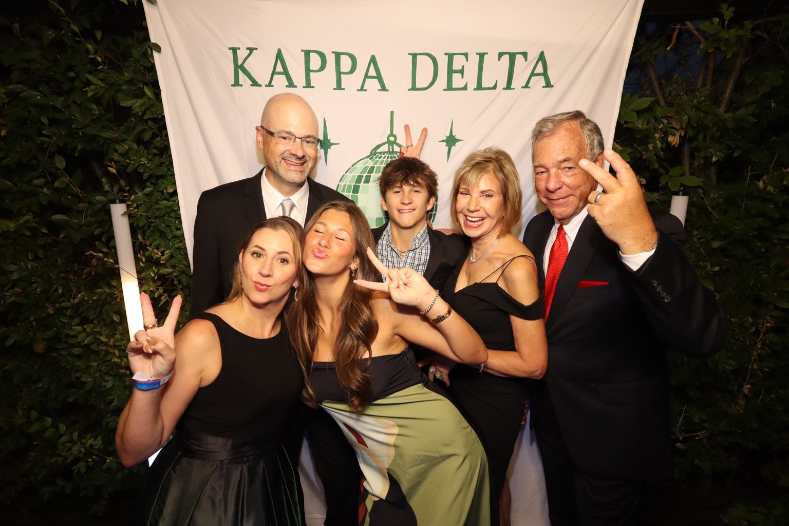 Six guests making playful poses in front of a Kappa Delta event backdrop.