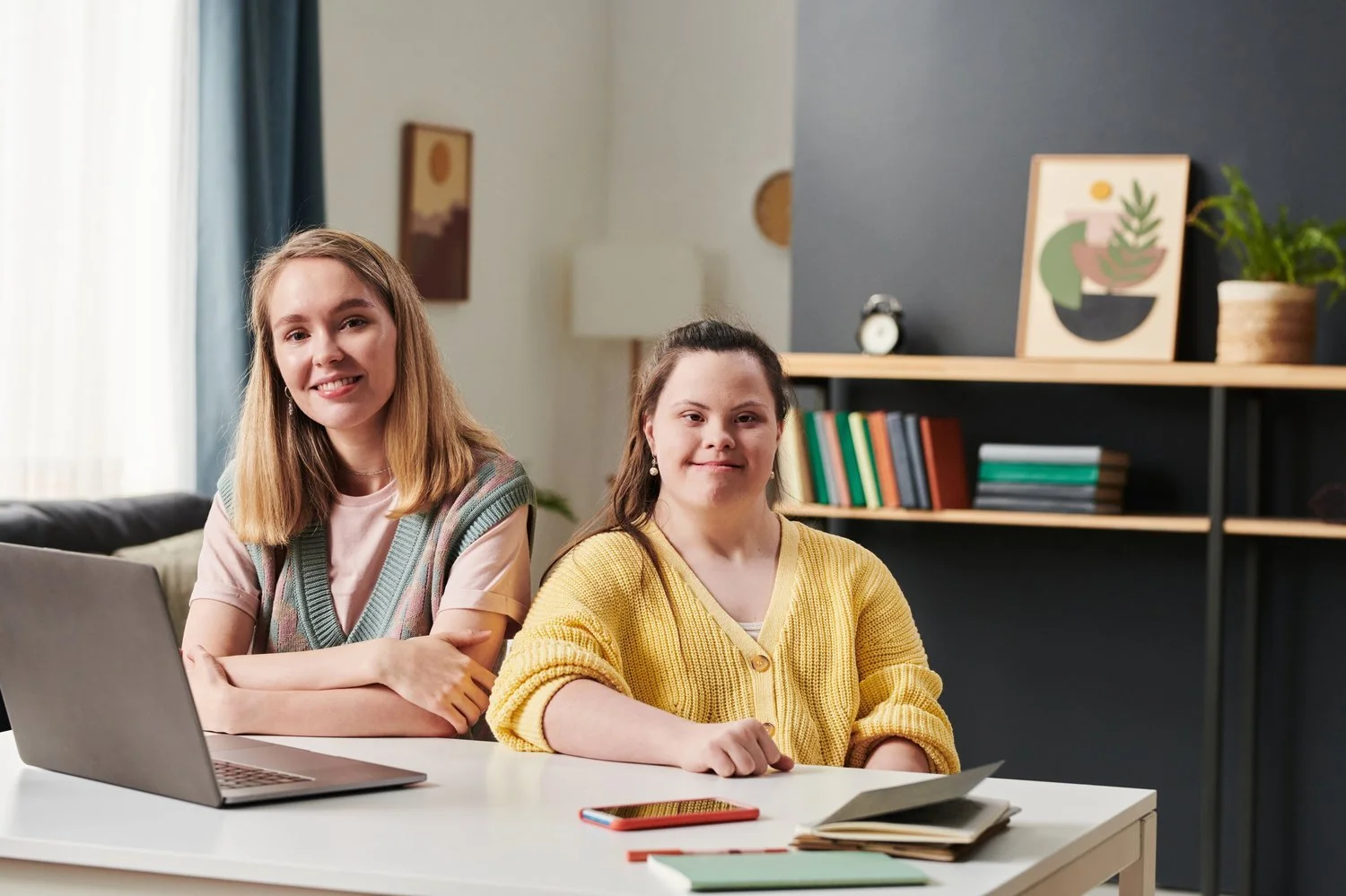 A woman and a young person with Down syndrome working together at a laptop