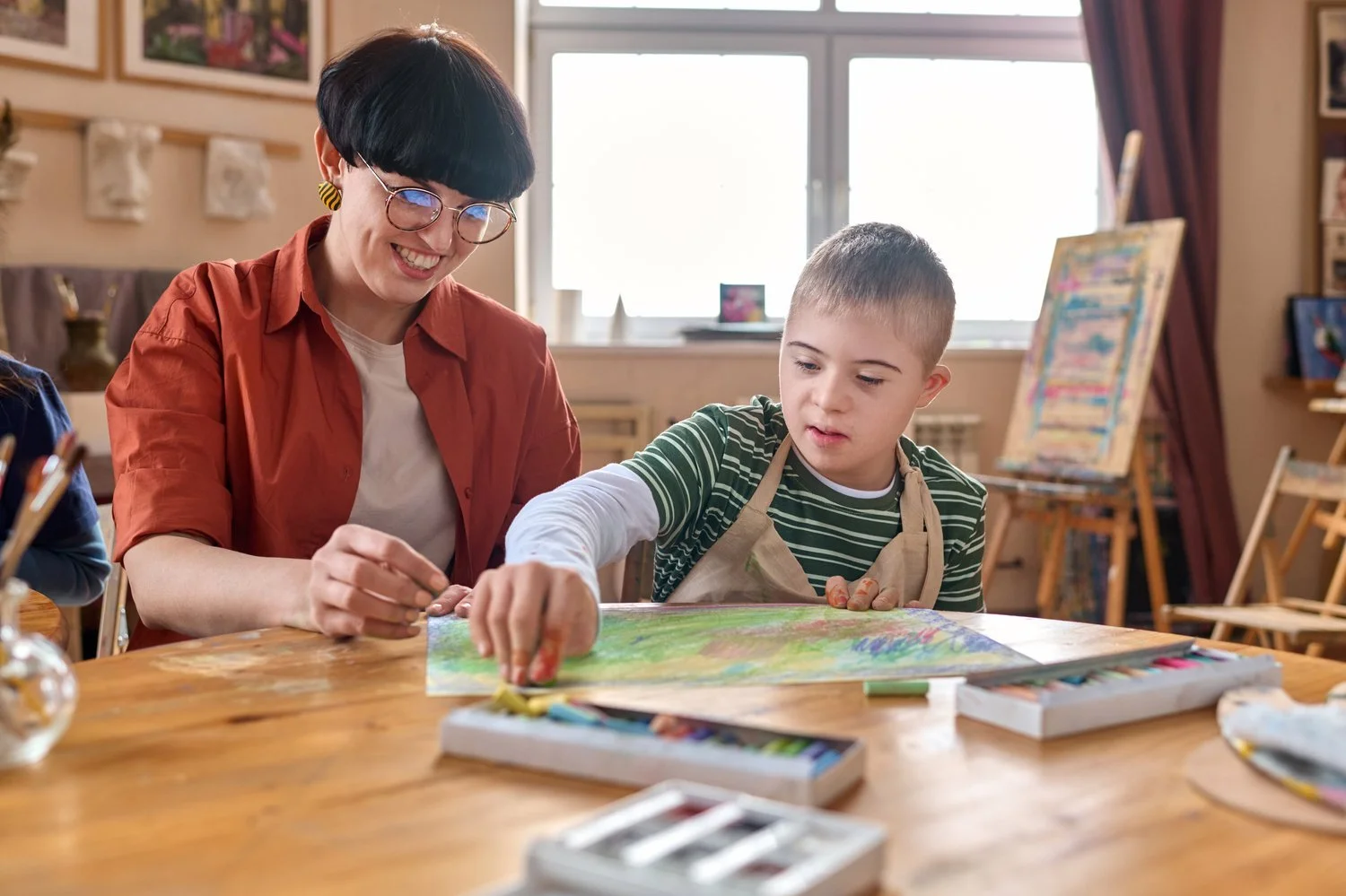 An adult and child painting together in an art class