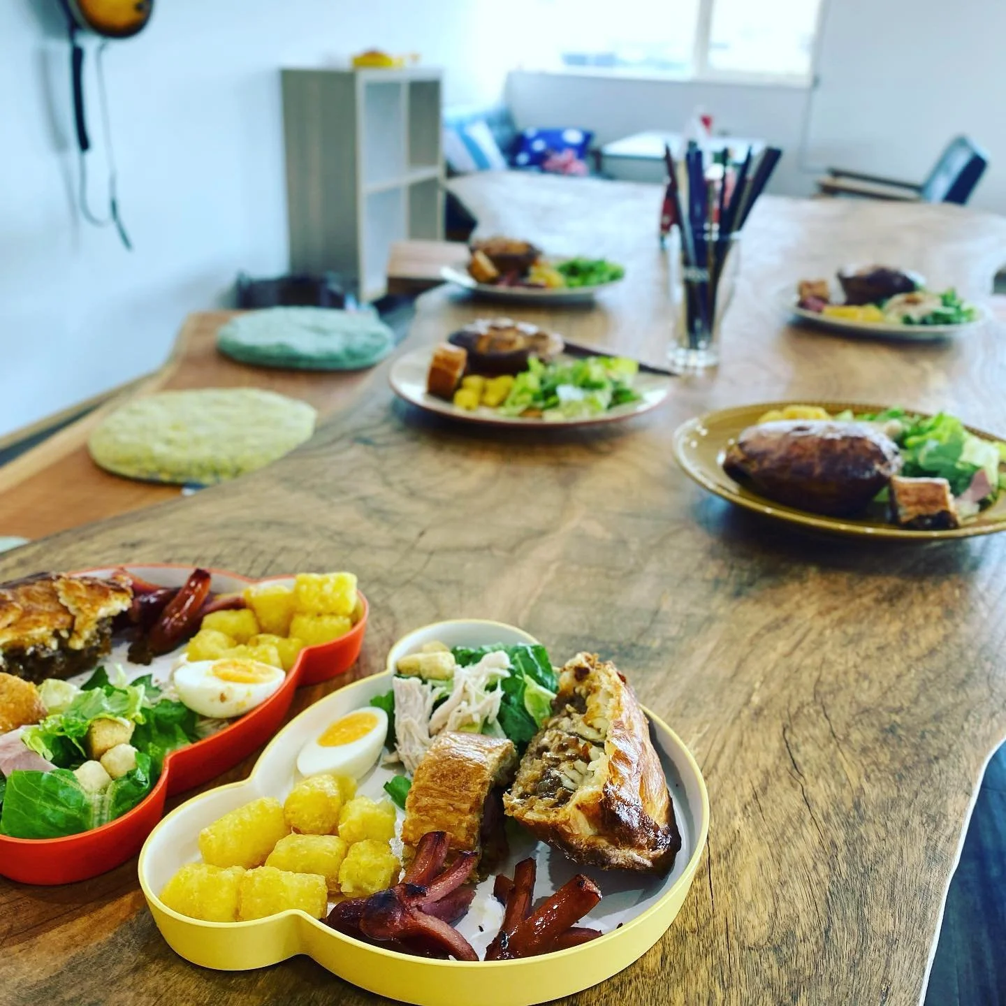 ケンが撮影した、料理のプレートが並ぶ木のカフェテーブル