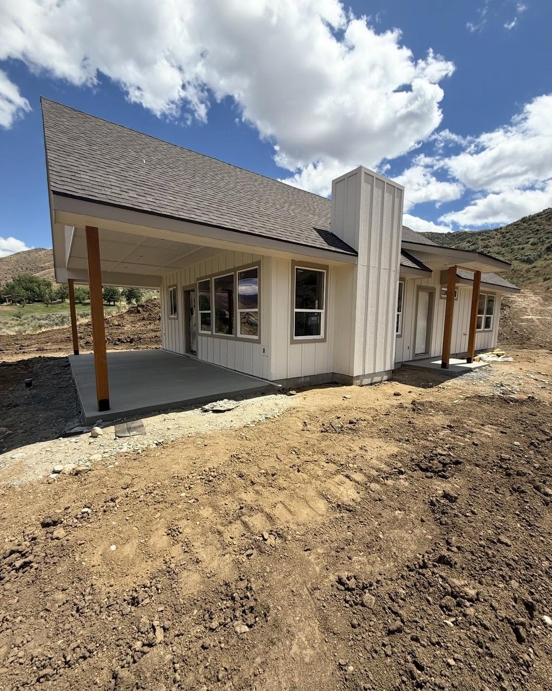 Custom home in Sweet, Idaho with three front gables, warm neutral siding, stone, and a covered timber porch