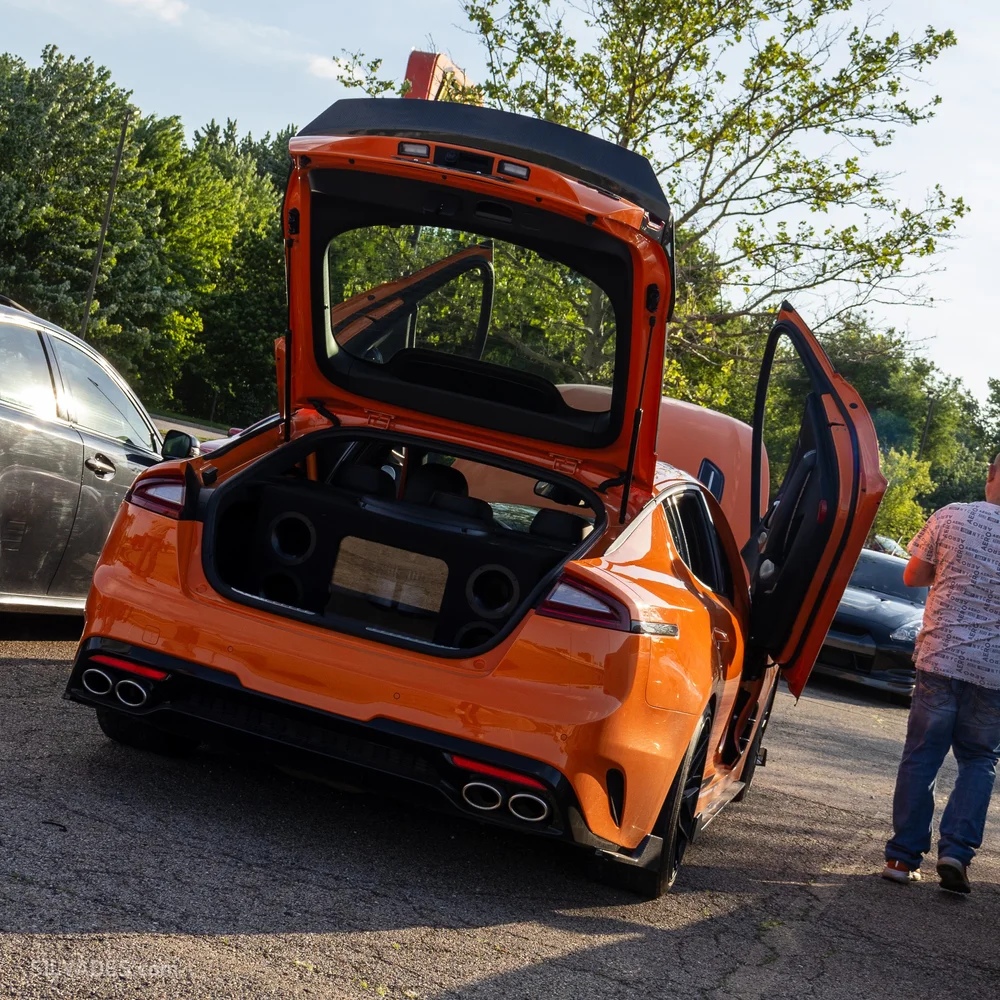 Orange Chevrolet C8 Corvette, rear three-quarter view with the hatch open