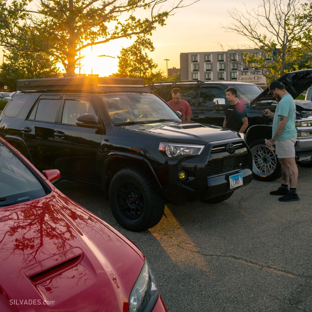 Sun flaring behind a black Toyota 4Runner at a car meet
