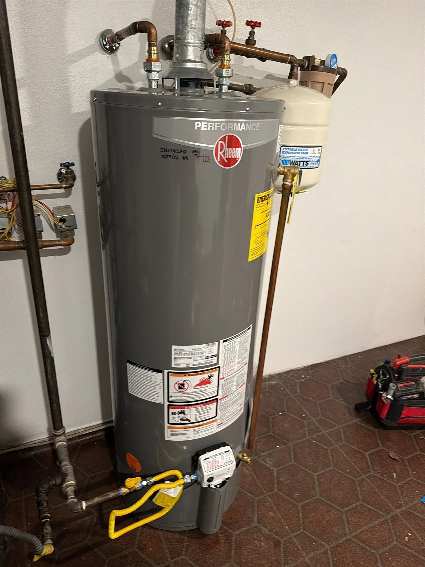 New tank-style water heater and connected piping installed by Atlas Plumbing Company