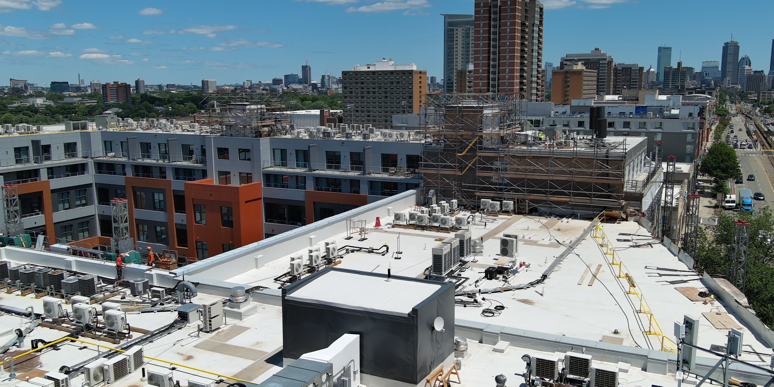Drone view of commercial roof on Commonwealth Avenue Brighton with Boston skyline and rooftop equipment