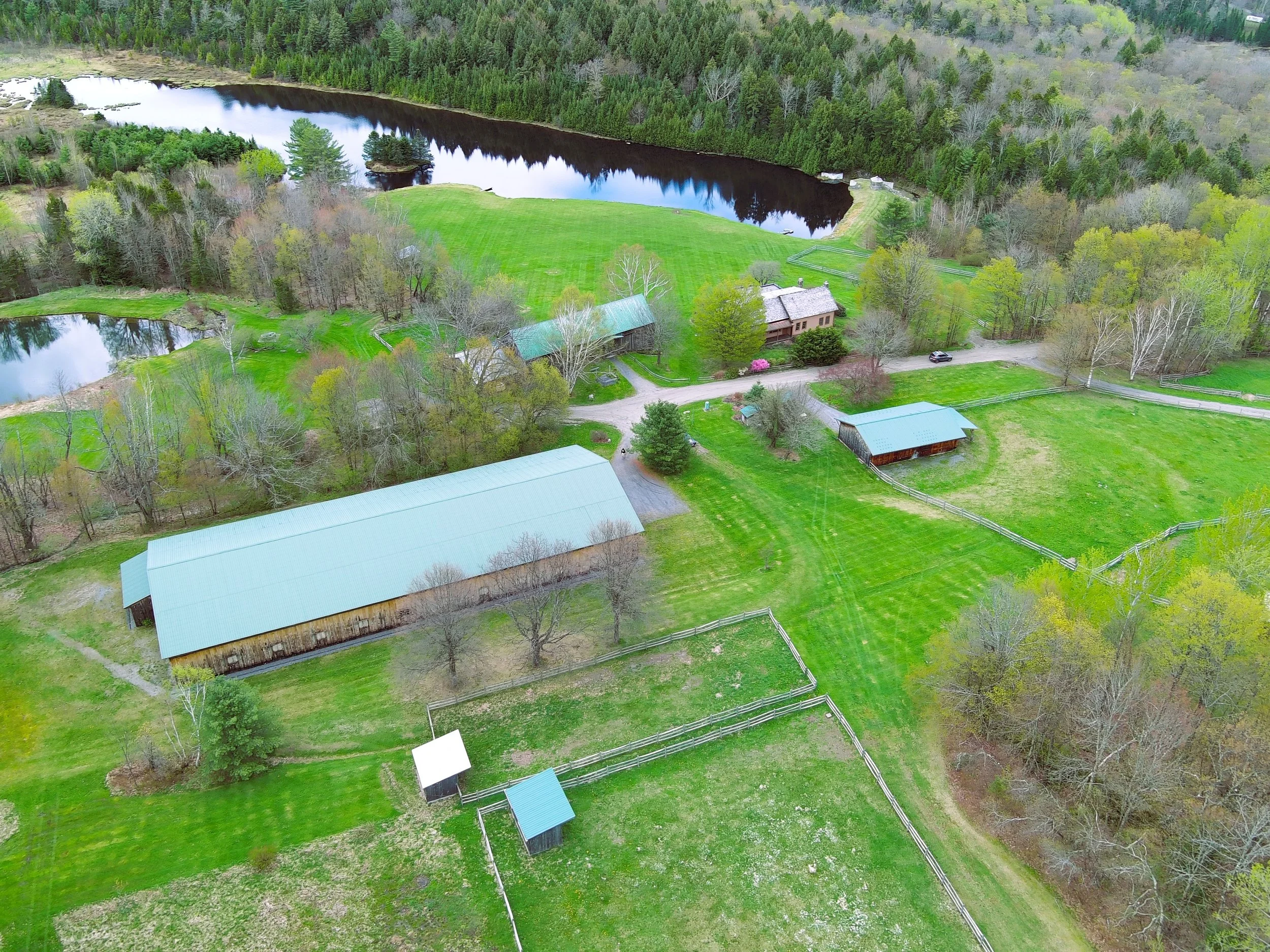 Aerial drone view of multi-building estate in Vermont showing roads, fields, and property layout