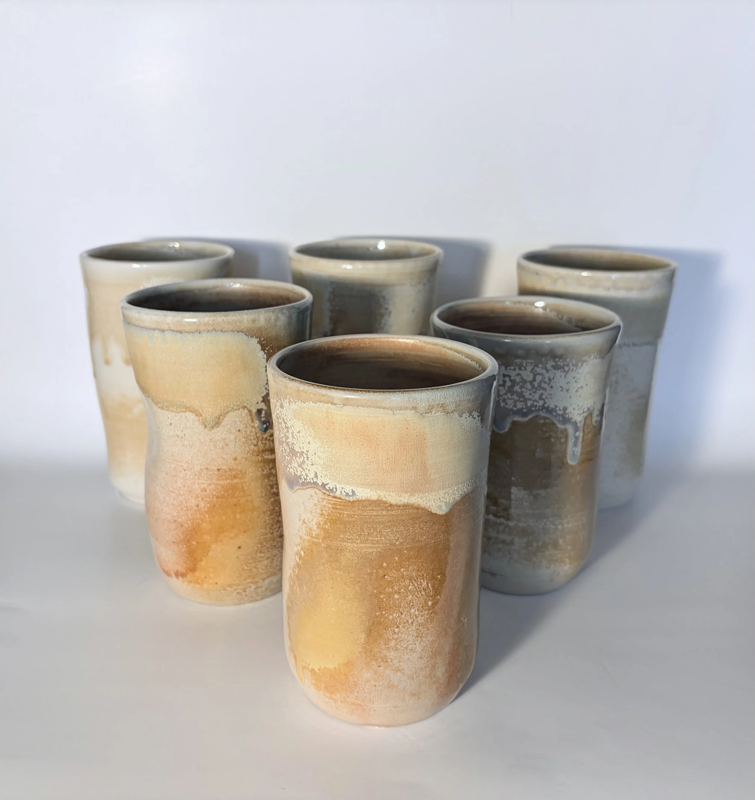 Collection of warm-toned wheel-thrown ceramic tumblers by Natalie Dahl