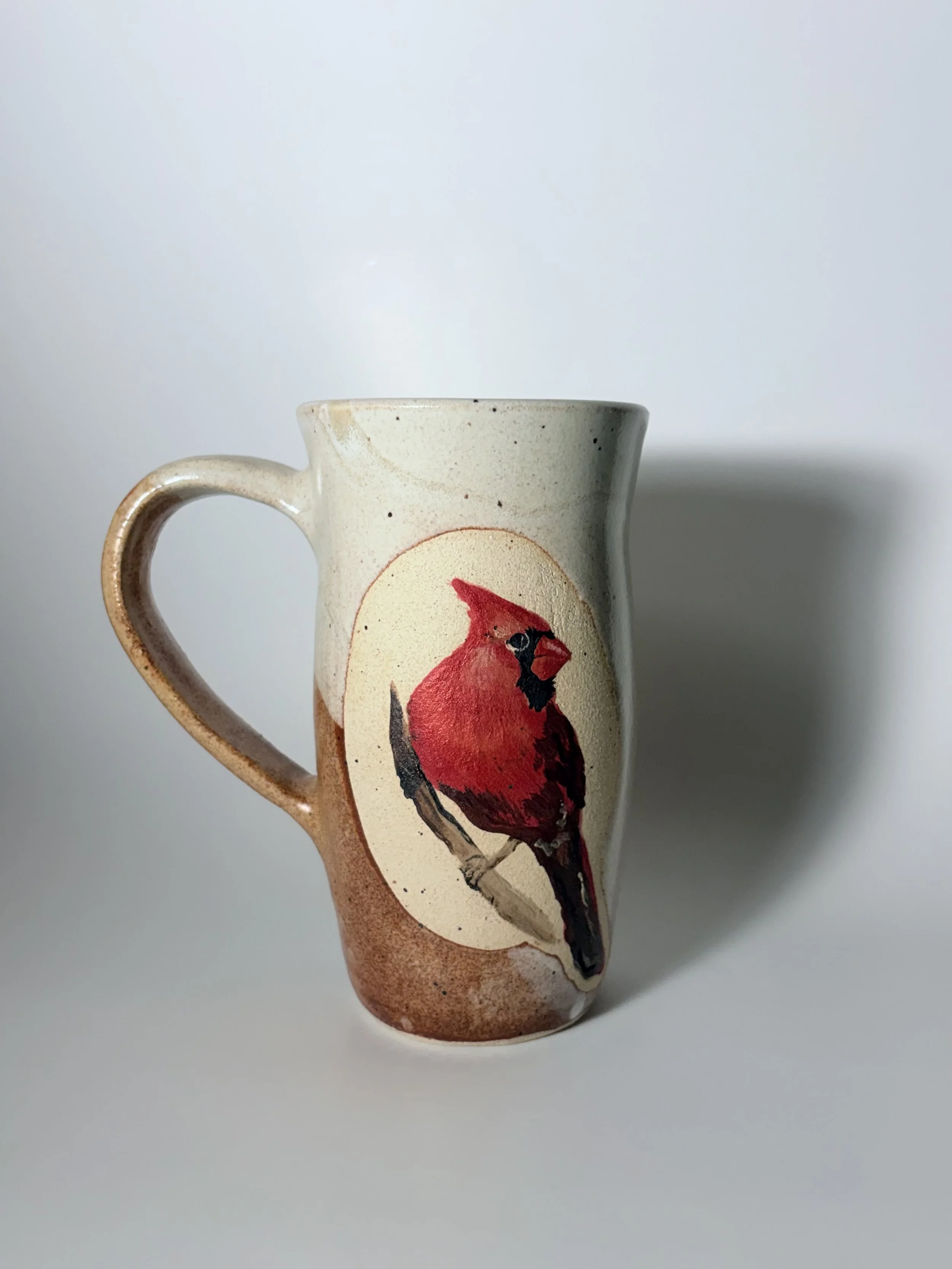 Cream-colored ceramic mug with a red and orange painted design by Natalie Dahl