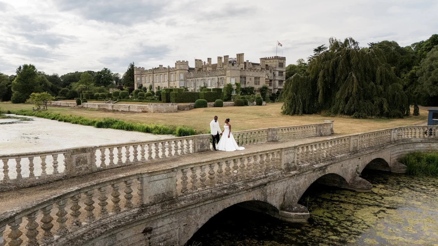 Newlyweds on a stone bridge in front of a castle wedding venue