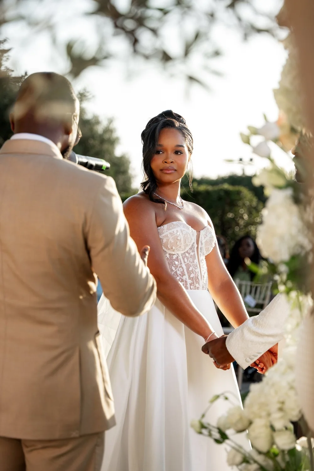 Bride and groom holding hands as they exchange vows, captured in hybrid wedding photography and film