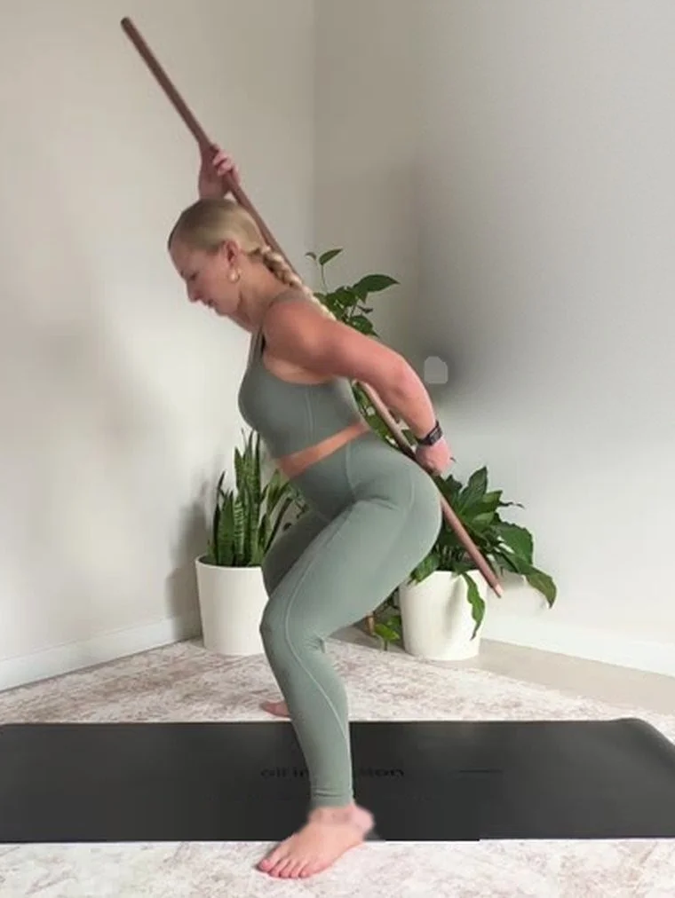Dr. Karla Kane demonstrating a loaded hip hinge with a dowel
