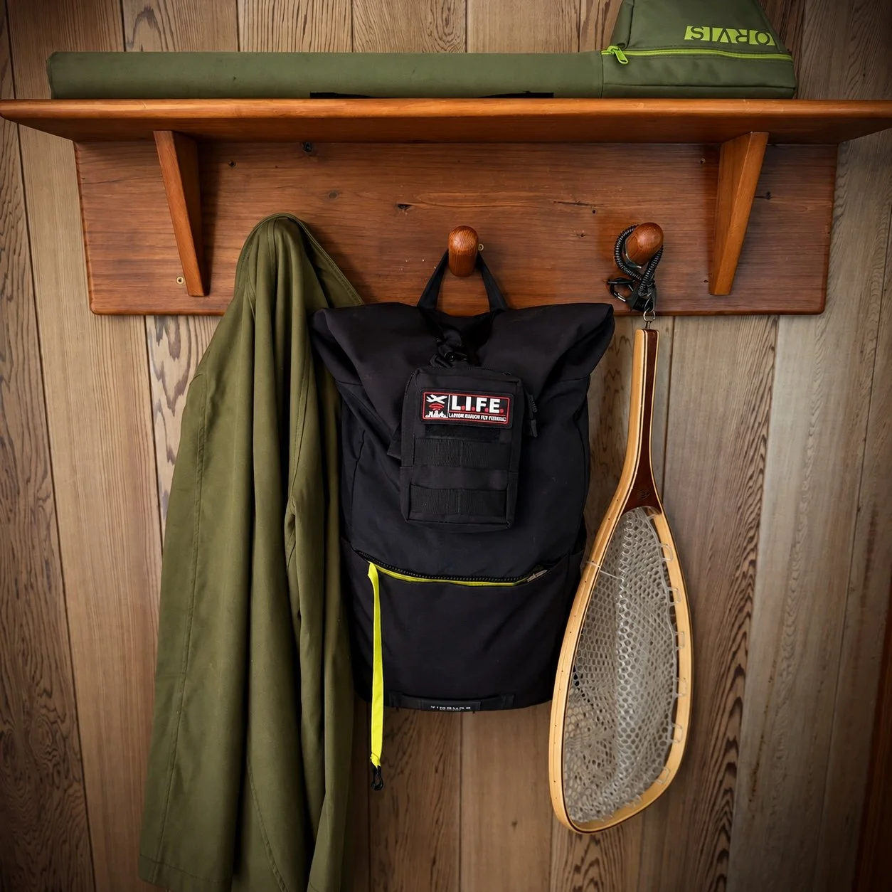 LIFE pouch attached to a backpack beside a jacket and fishing net