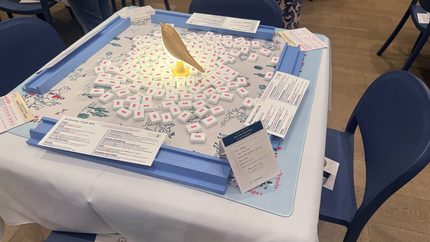 Cream mahjong mat with cactus print, blue racks and white tiles at an itsaMahjing table in Austin