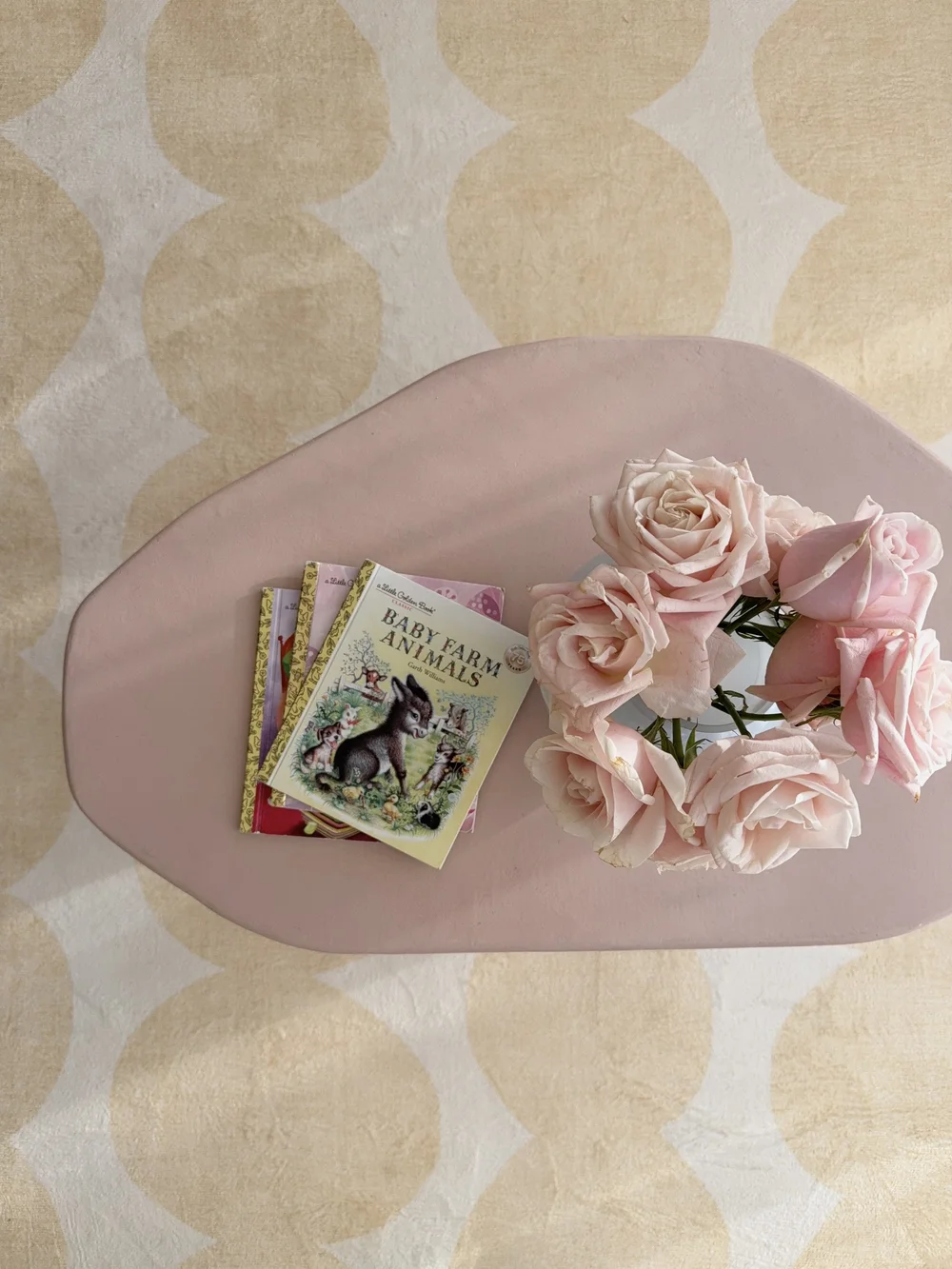 Top view of a pink microcement coffee table styled with flowers and books
