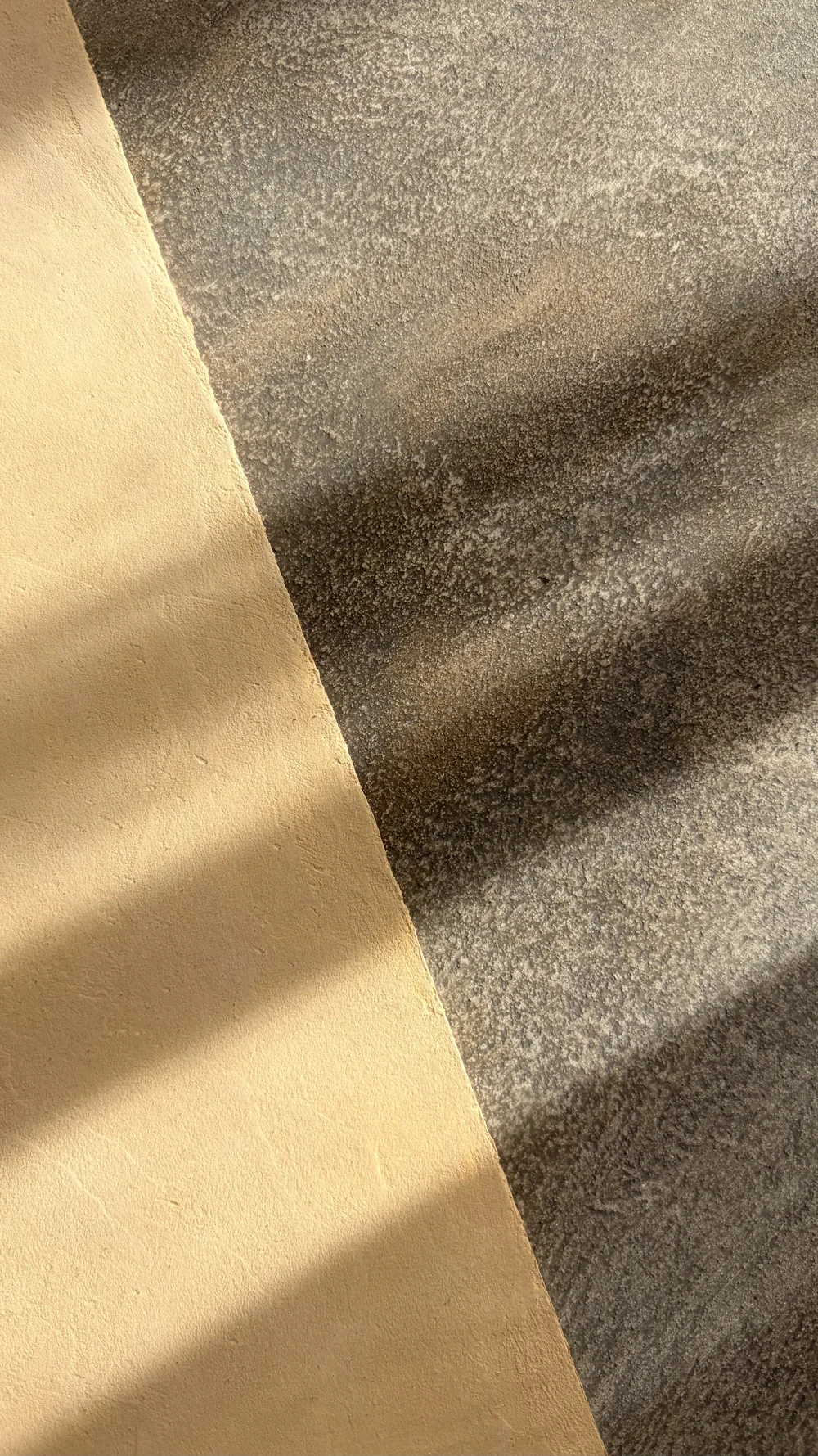 Gold-toned and charcoal decorative finish samples crossed by soft shadows