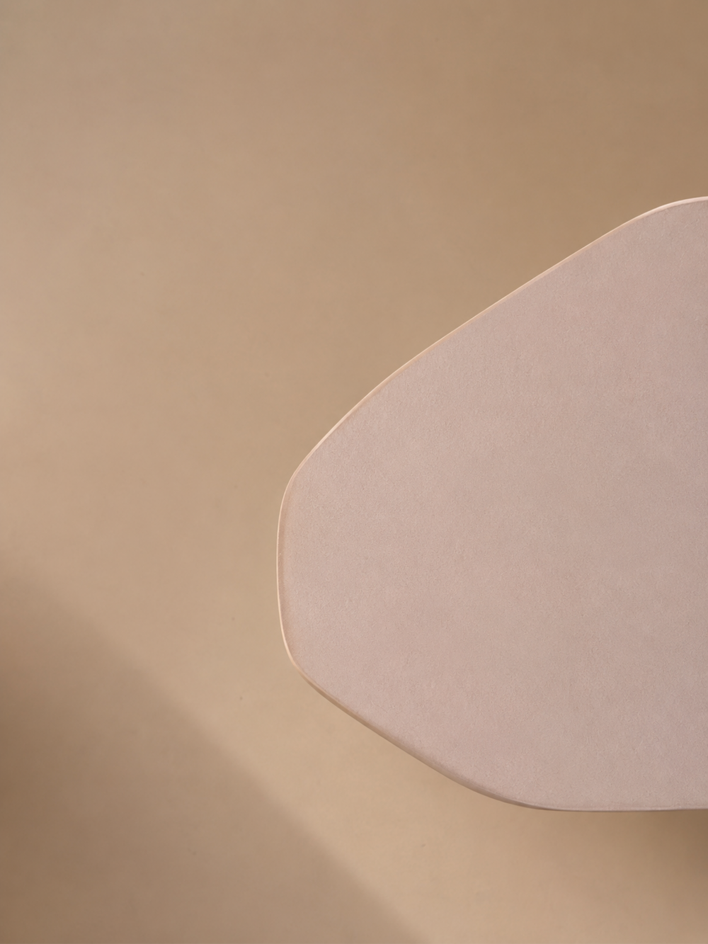 Close-up of the rounded edge and soft pink finish of a microcement table