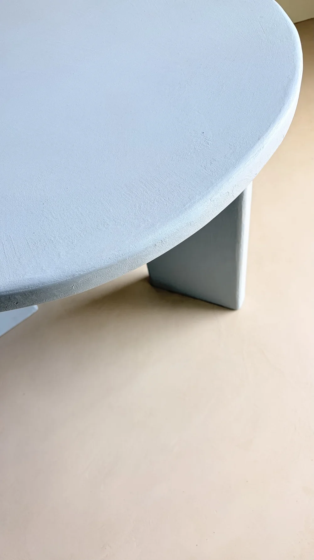 Close-up of a rounded blue microcement tabletop and table leg