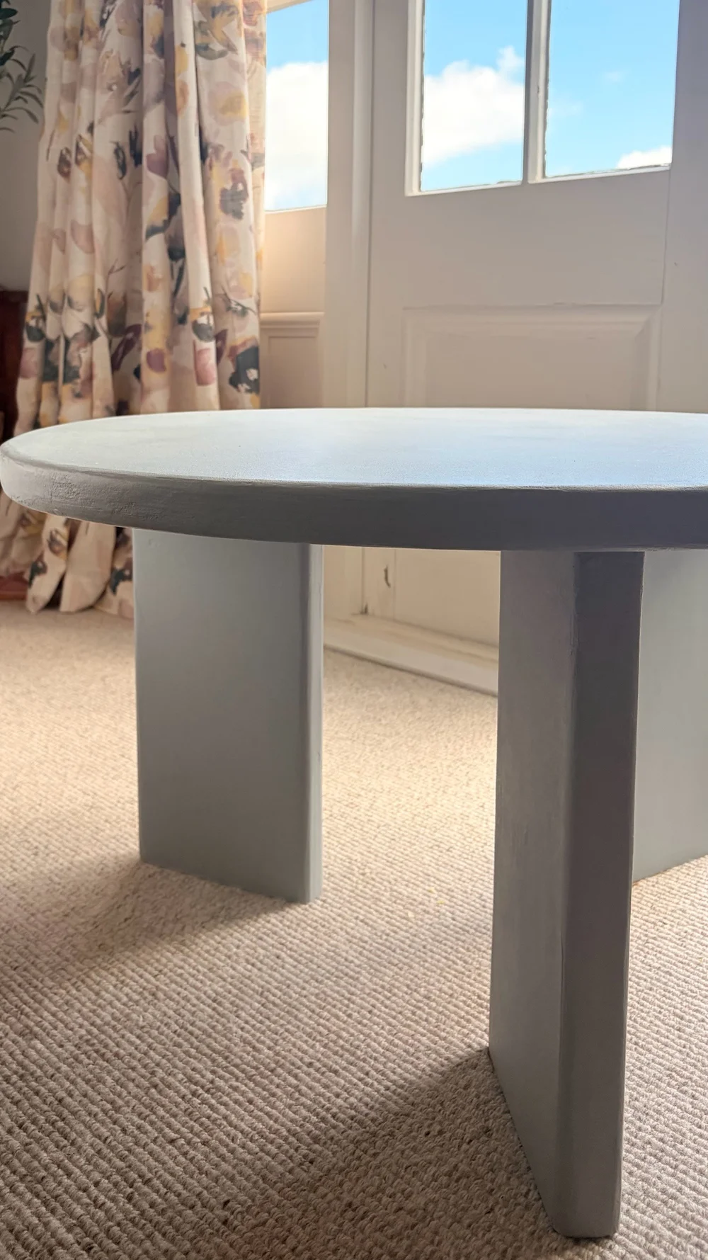 Blue-grey custom microcement table with rounded top photographed in a natural interior
