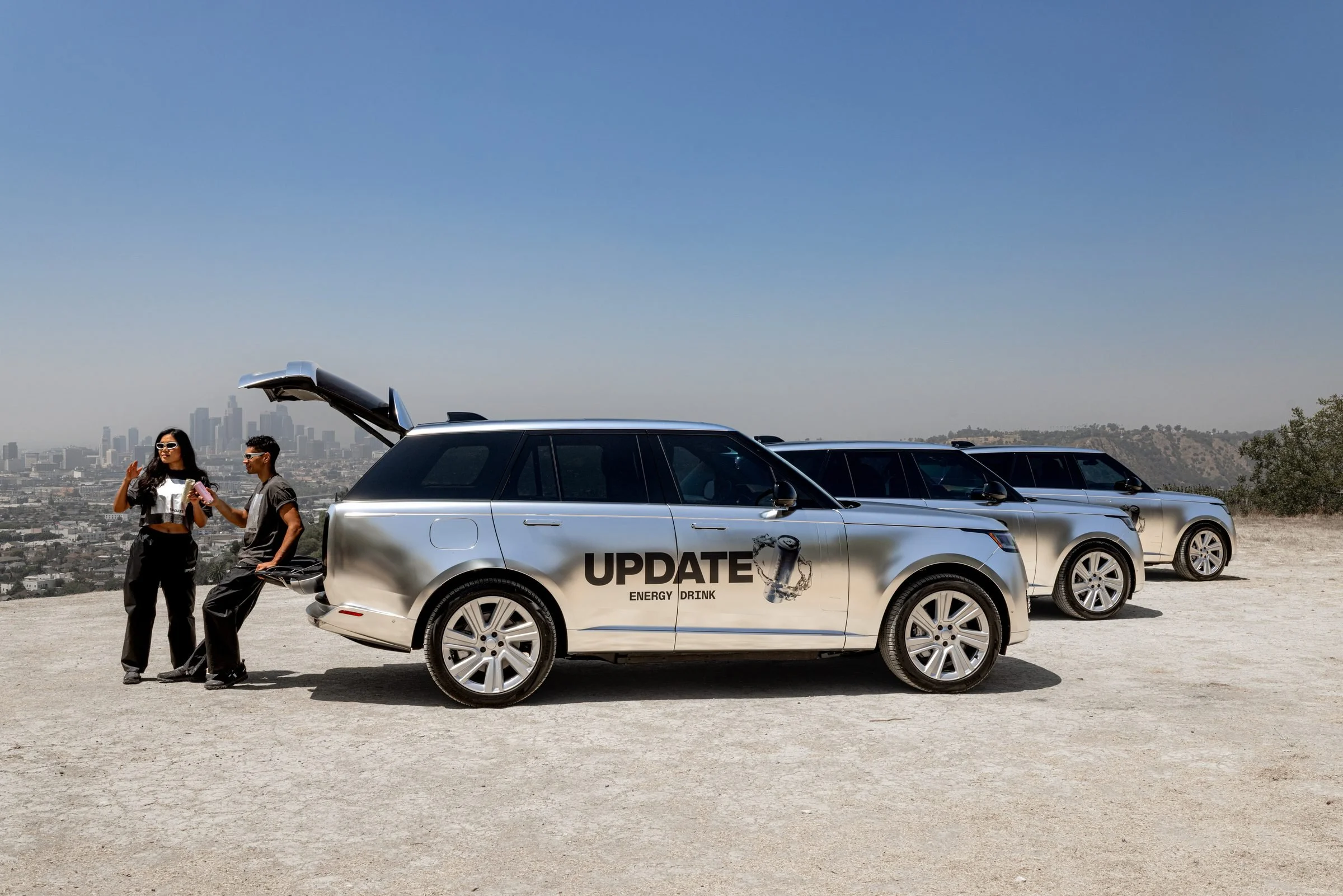 Two UPDATE ambassadors in conversation at the open tailgate of a branded UPDATE Range Rover