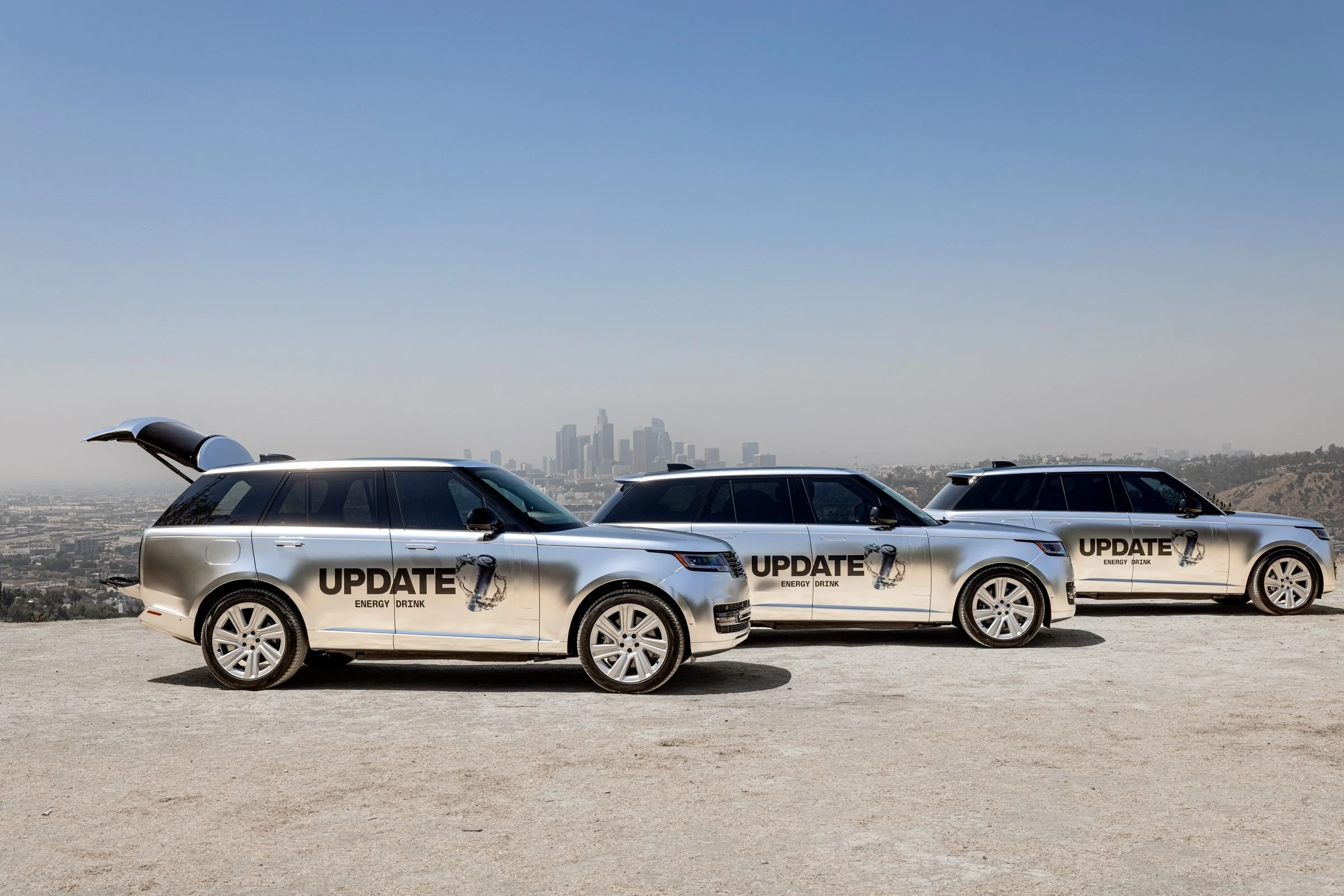Three UPDATE Energy Drink-wrapped Range Rovers lined up on a hilltop above Los Angeles, the lead SUV's tailgate open