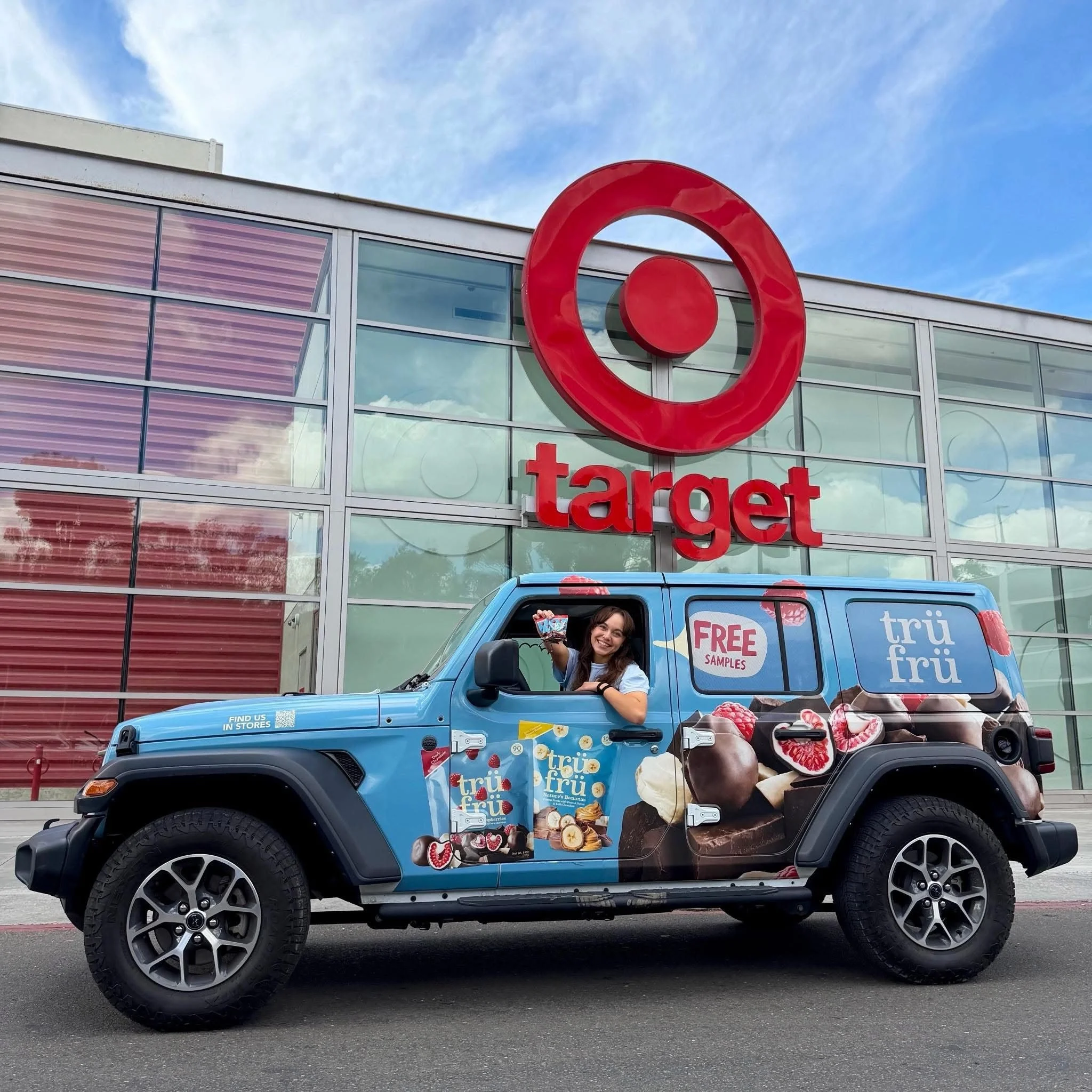 Tru Fru-wrapped Jeep Wrangler parked outside a Target store, with an ambassador waving product from the driver's window