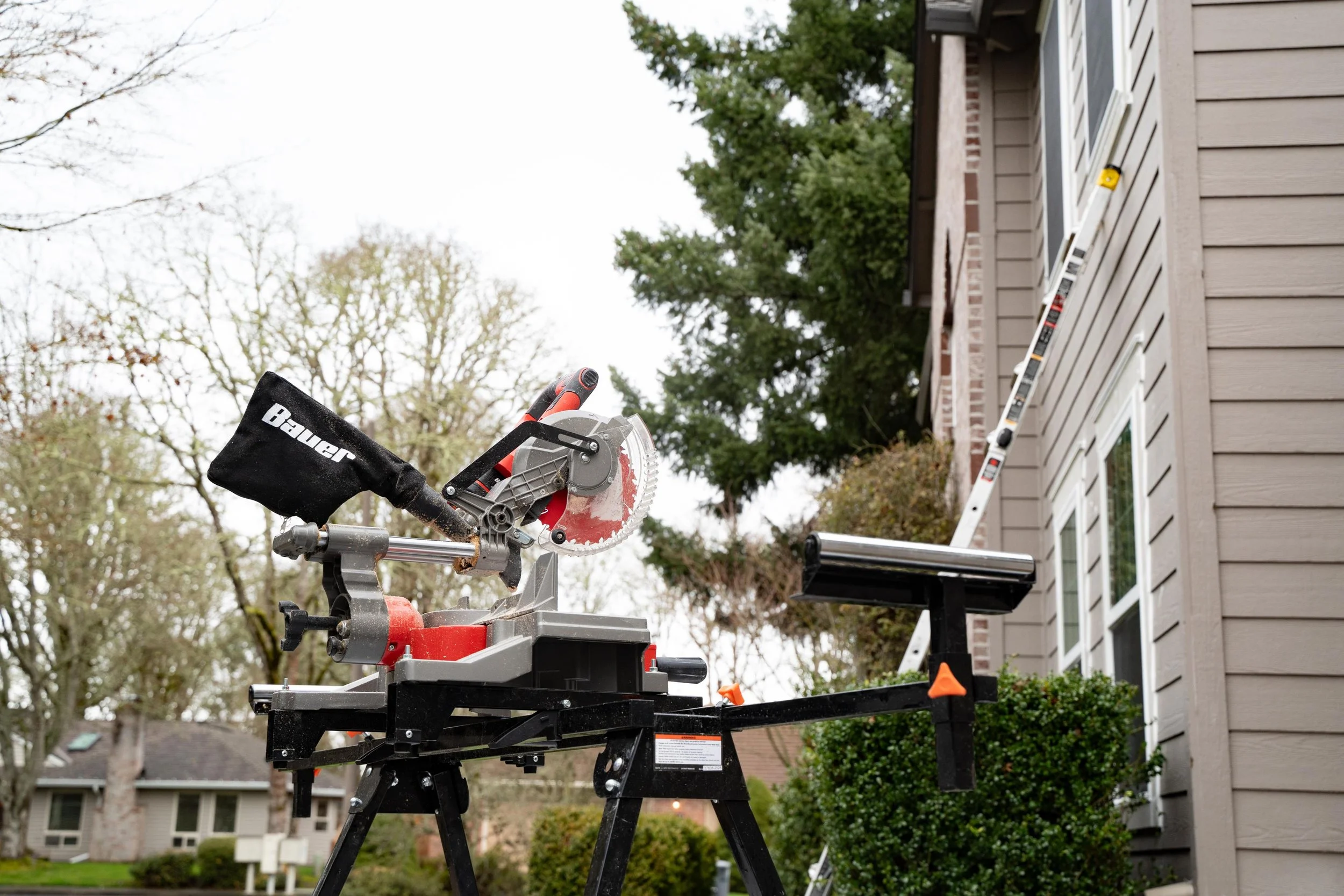 Miter saw set up on its stand beside a Portland home during a window installation