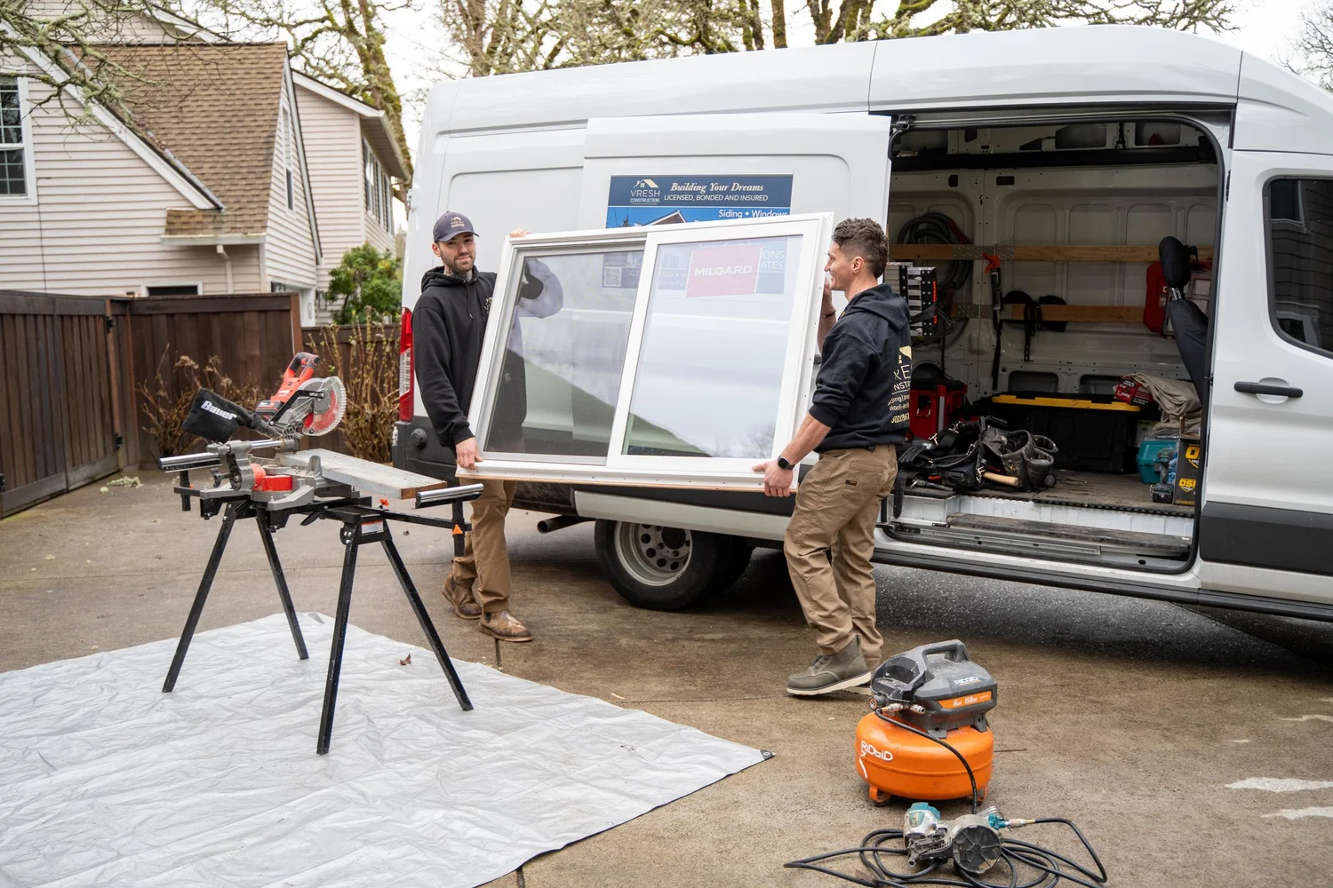 VResh Construction crew carrying a new window unit from the company van to a Portland window replacement job