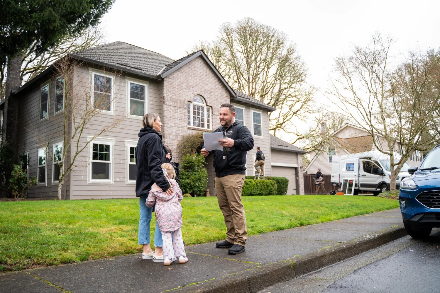 Vlad of VResh Construction going over a written window estimate with a homeowner and her daughter outside their Portland home
