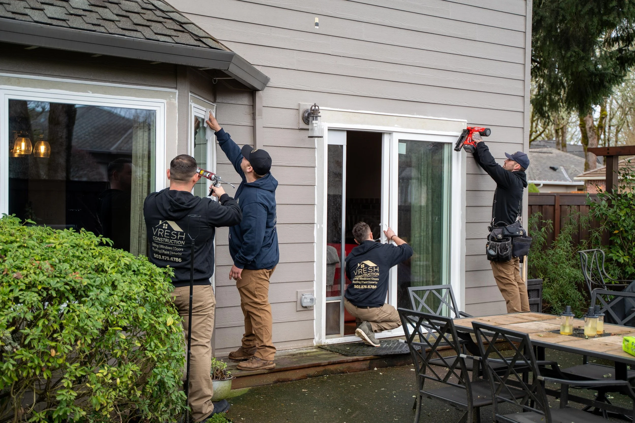 VResh Construction crew working on a sliding glass door and patio windows at the back of a Portland home