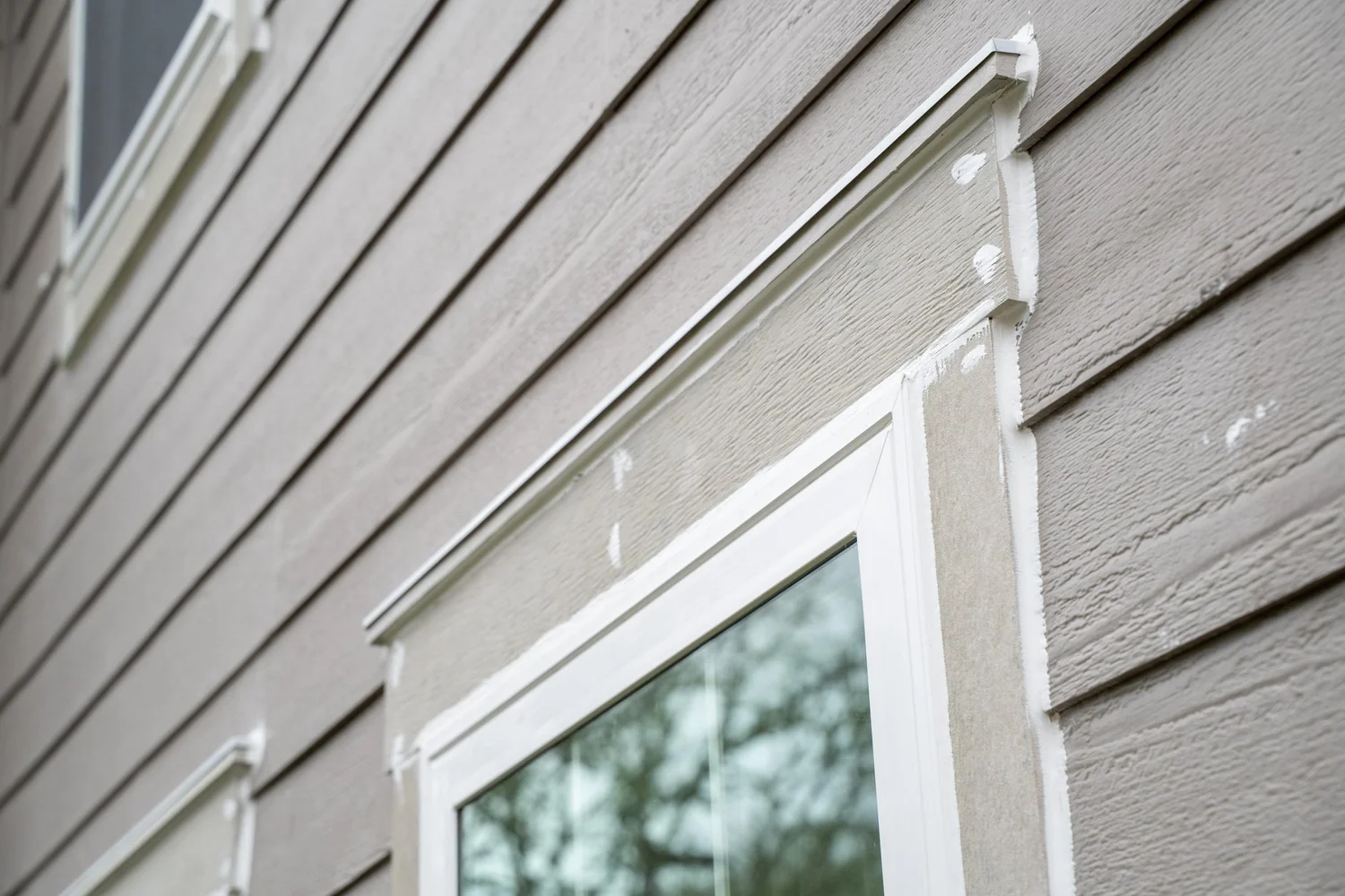 Close-up of a new white window frame and fresh trim set into lap siding on a Portland home