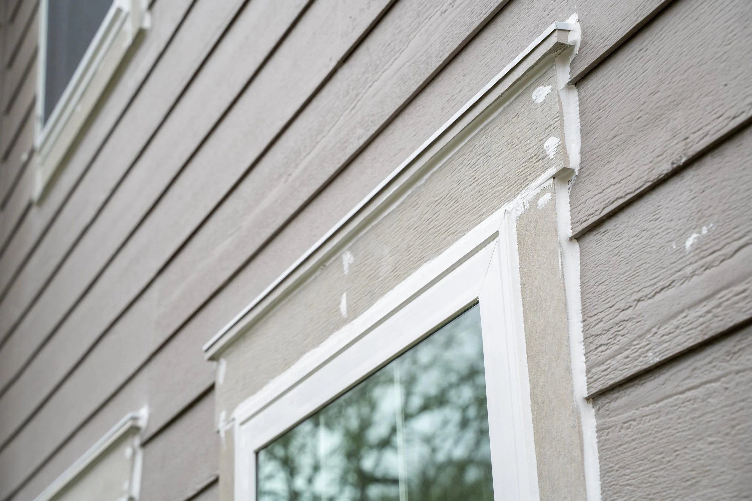 Close-up of new white window trim and fresh siding seams around a replacement window on a Portland home