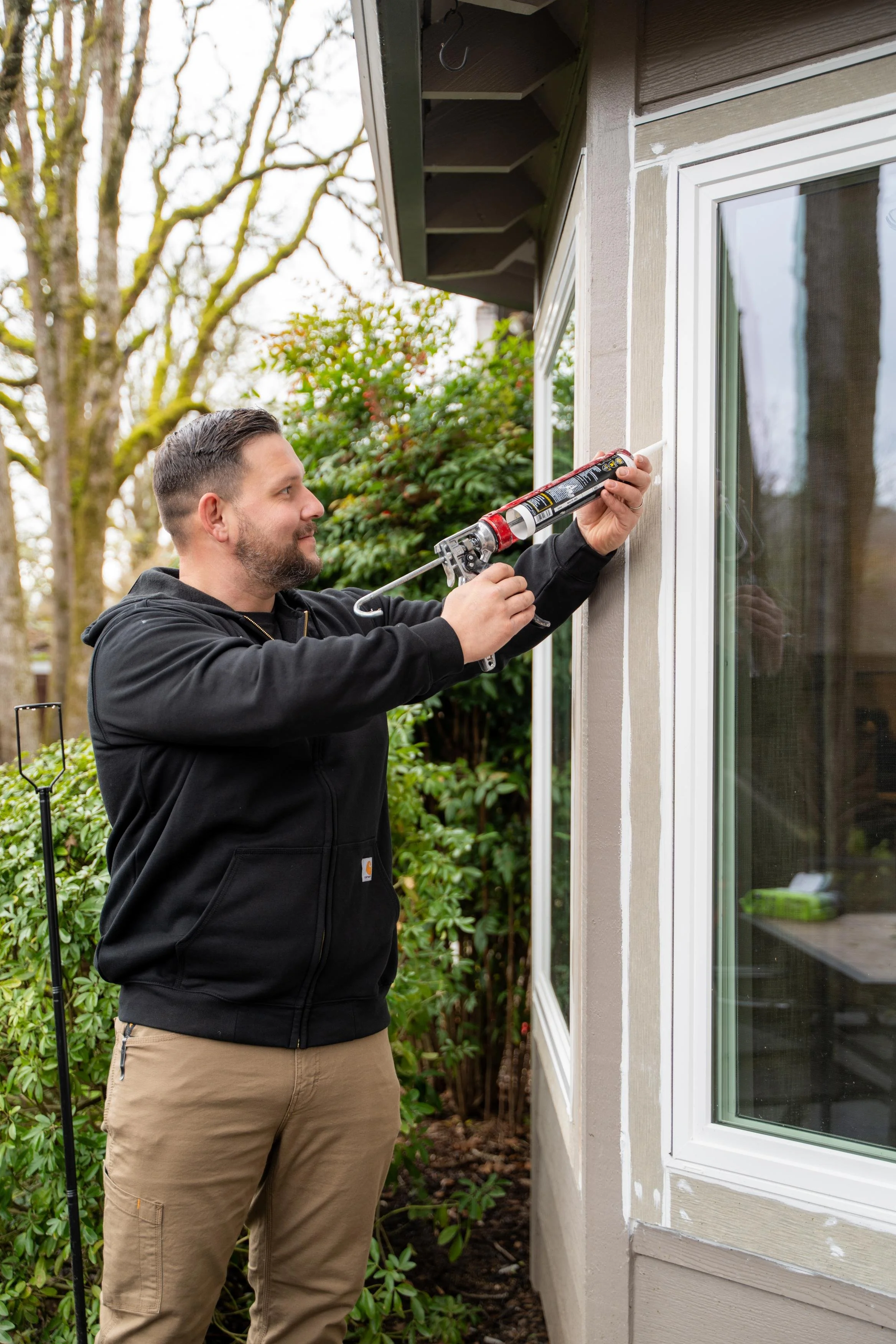 Vlad of VResh Construction sealing the frame of a sliding glass door with a caulking gun, for sliding glass door repair in Beaverton, OR