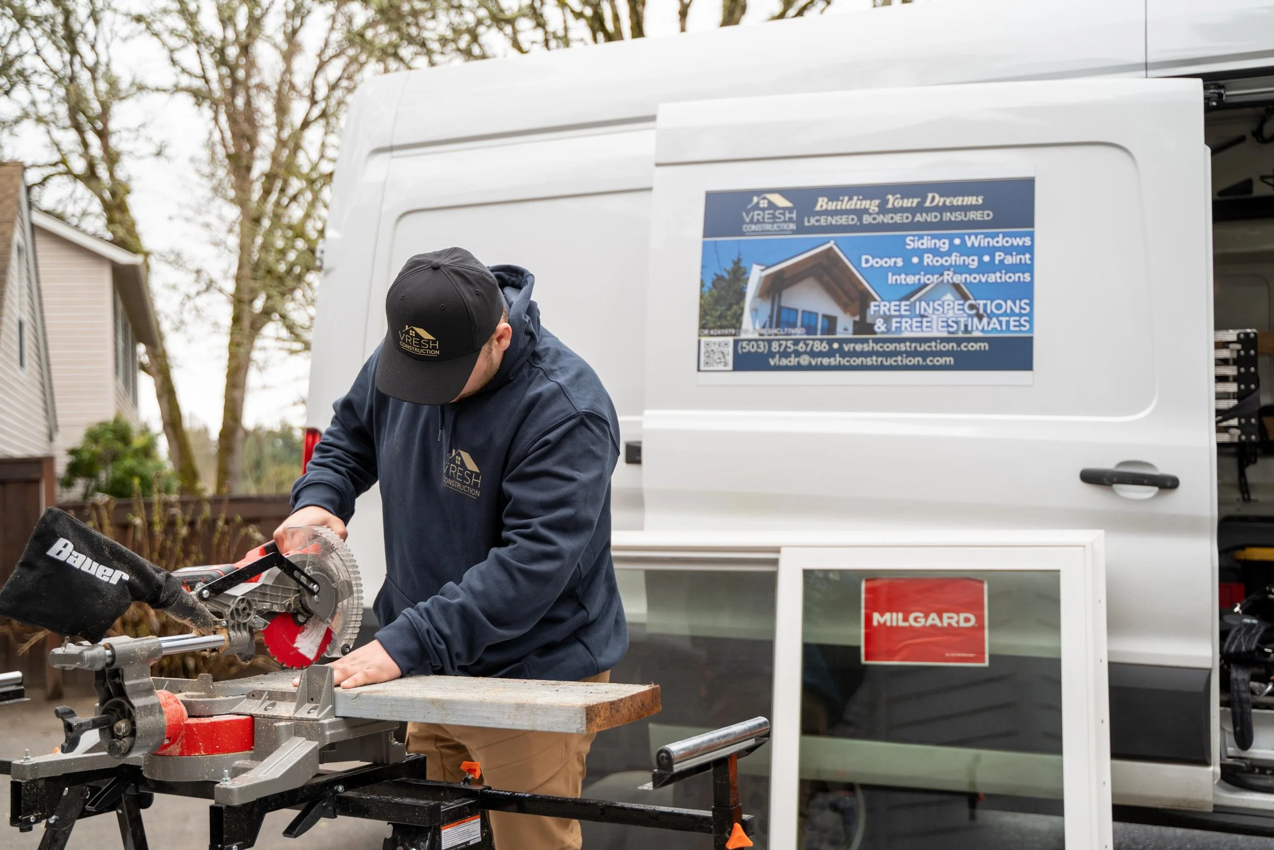 VResh Construction technician cutting trim on a miter saw next to a new Milgard window unit
