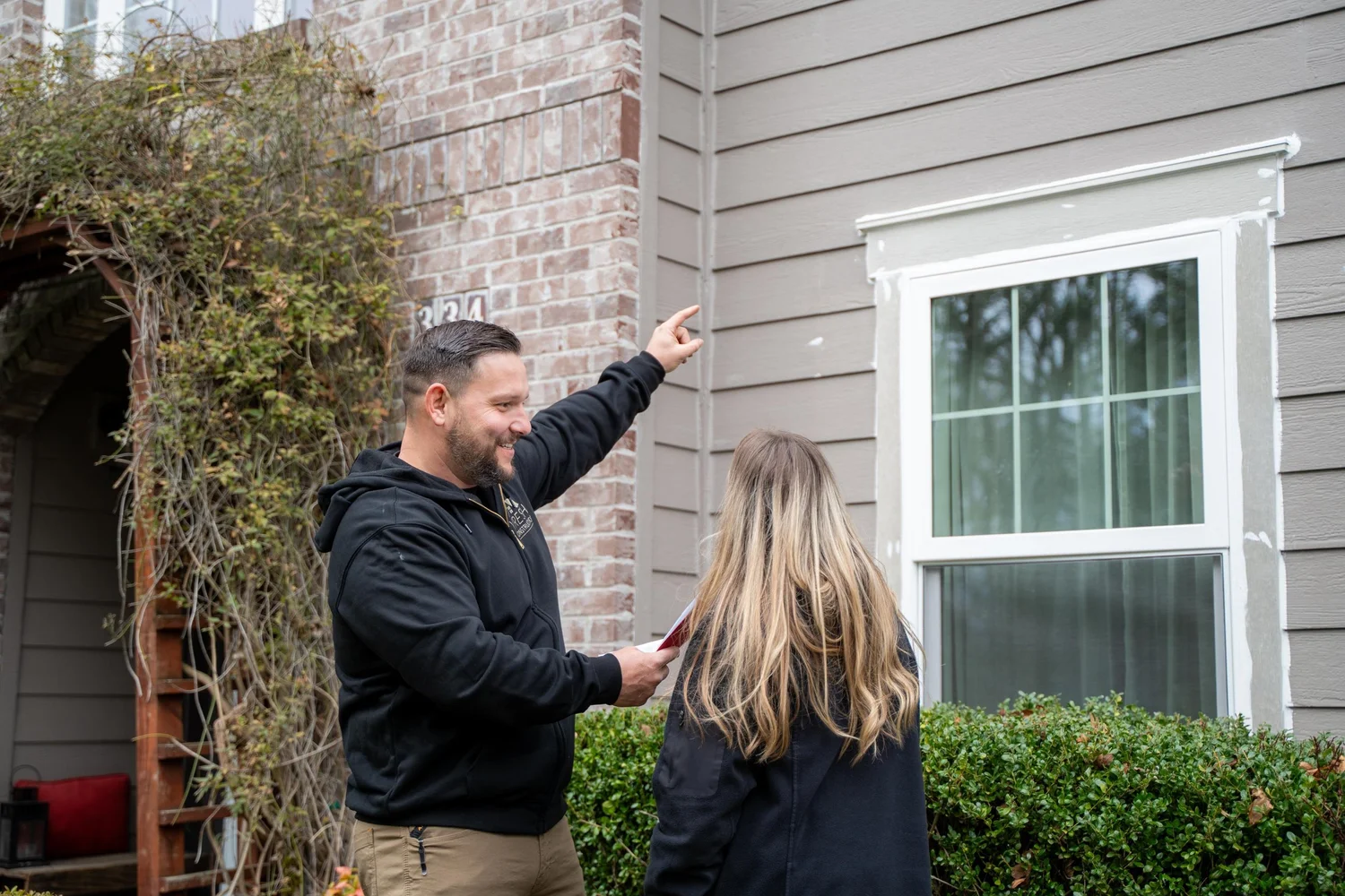 Vlad of VResh Construction pointing out a window to a Portland homeowner during a free window estimate