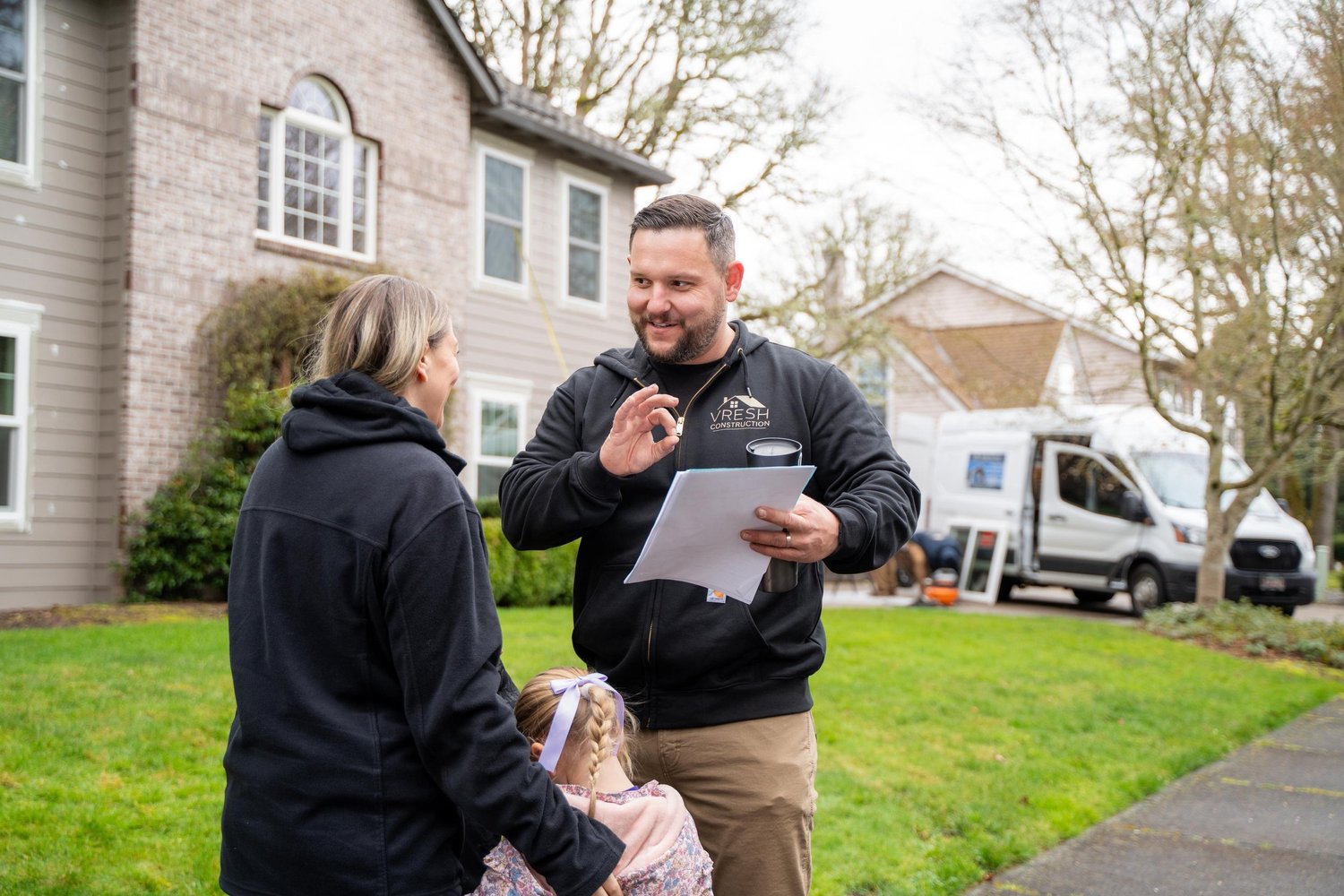 VResh owner going over a written estimate with a homeowner and her daughter on their front lawn