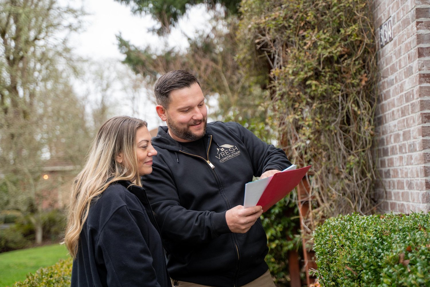 Homeowner reviewing a written VResh Construction estimate with Vlad outside her Portland home