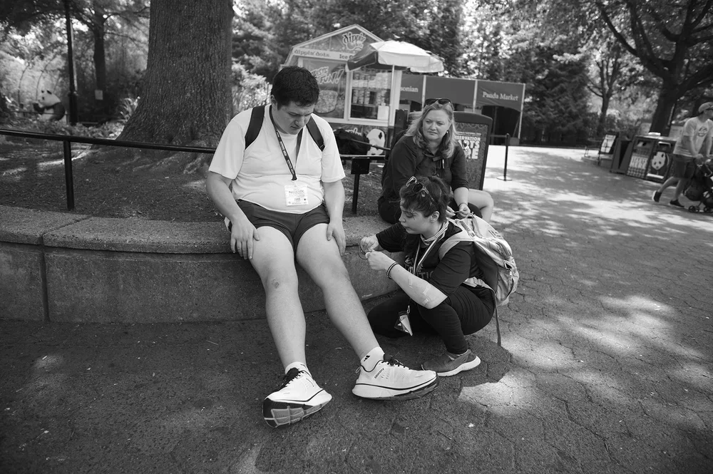 Jadyne kneels to bandage Luke's scraped knees.